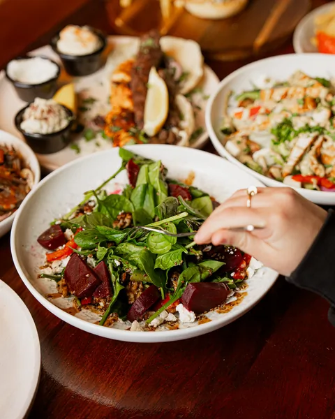 Friends reaching into a table of salads and grills at Beit Baytak