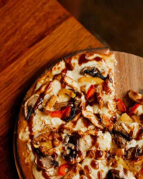 BBQ chicken pizza with a barbecue sauce drizzle on a wooden board