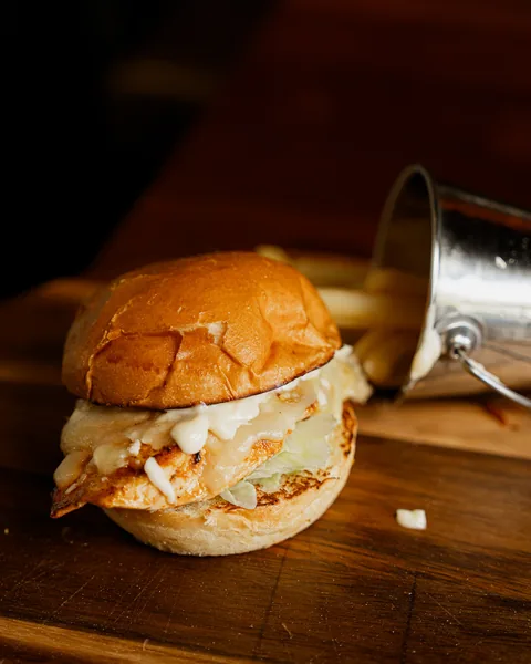 Chicken burger on a wooden board with chips