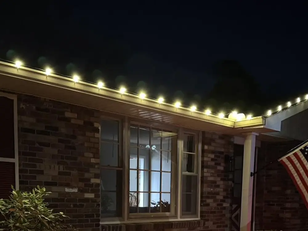 Warm white Christmas lights along a brick home roofline