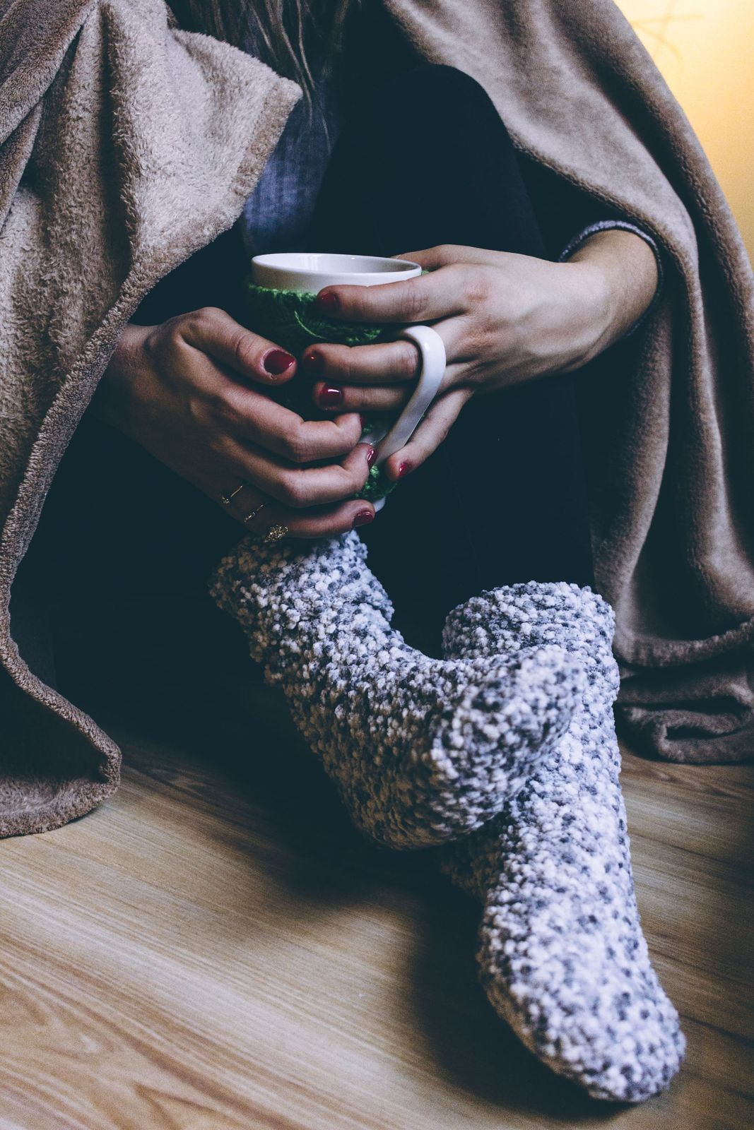 Feet in warm wool socks under a blanket
