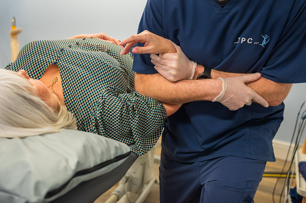 A friendly clinician guiding a patient through shoulder rehabilitation