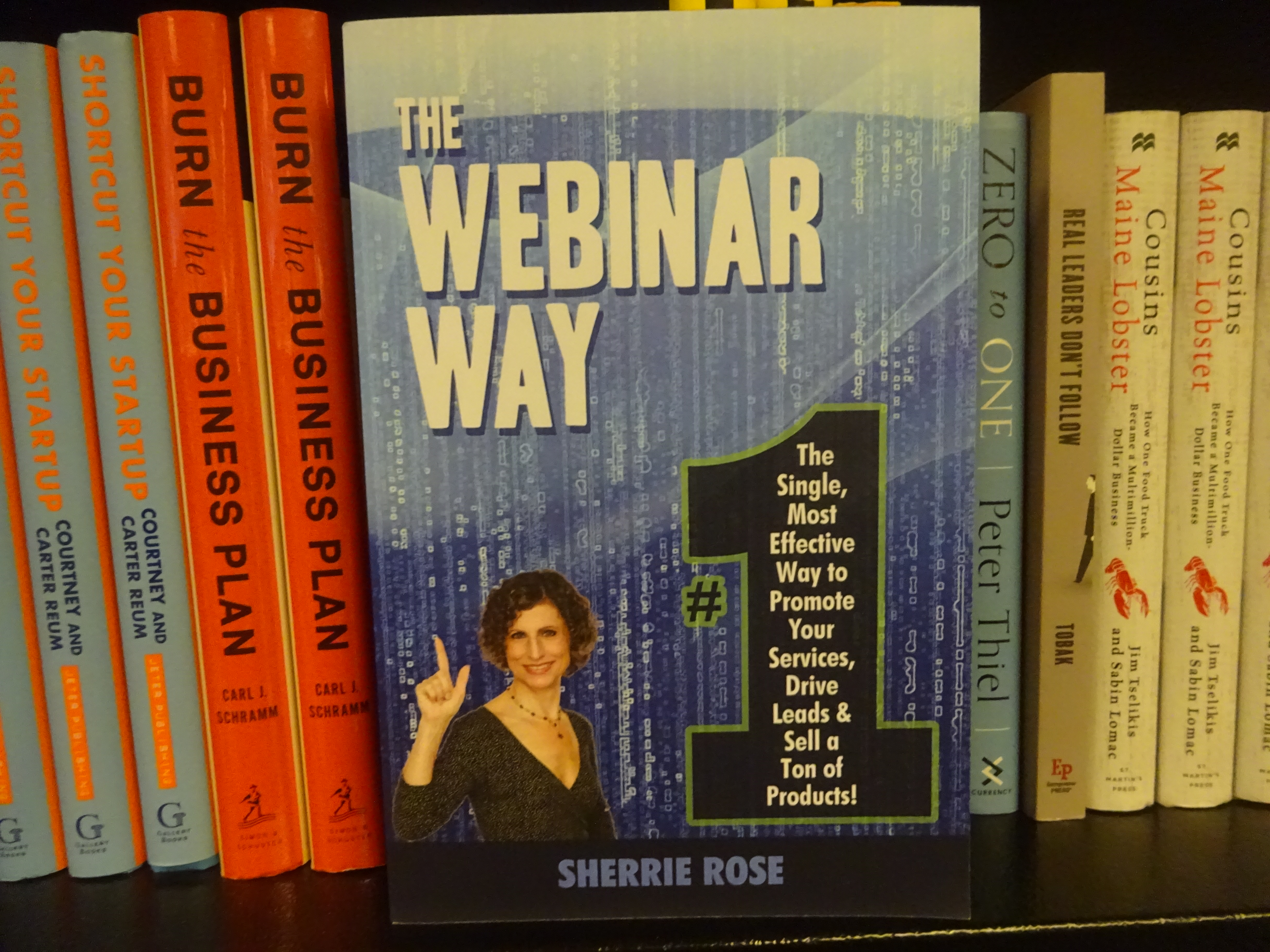 Photo of book, The Webinar Way by Sherrie Rose, author, on a bookshelf with other books