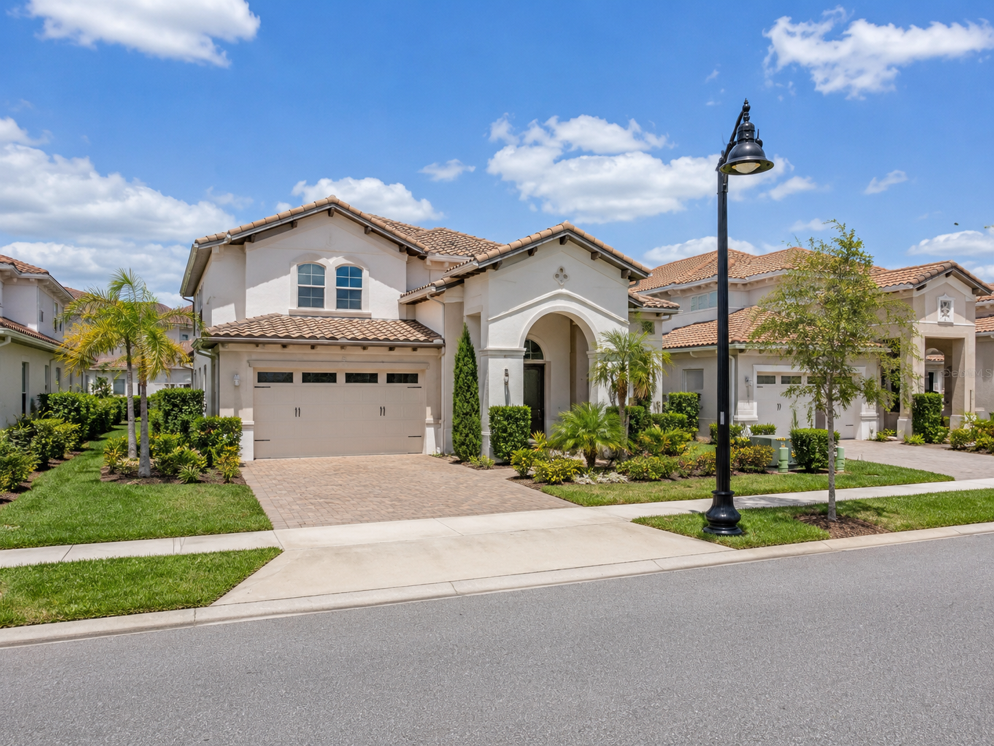 Eagle Creek Lake Nona home with Mediterranean-style architecture, tile roof, paver driveway, palm trees, and manicured landscaping in Orlando, Florida.