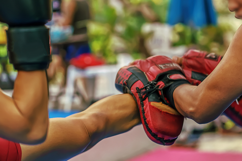 Kid-doing-a-round-kick-on-muay-thai-pads-self-defense-practice Kid-doing-a-round-kick-on-muay-thai-pads-self-defense-practice