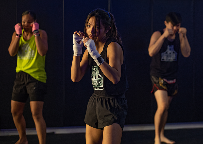 Group of students wearing hand wraps in a guarded stance during a Muay Thai class warm up Group of students wearing hand wraps in a guarded stance during a Muay Thai class warm up