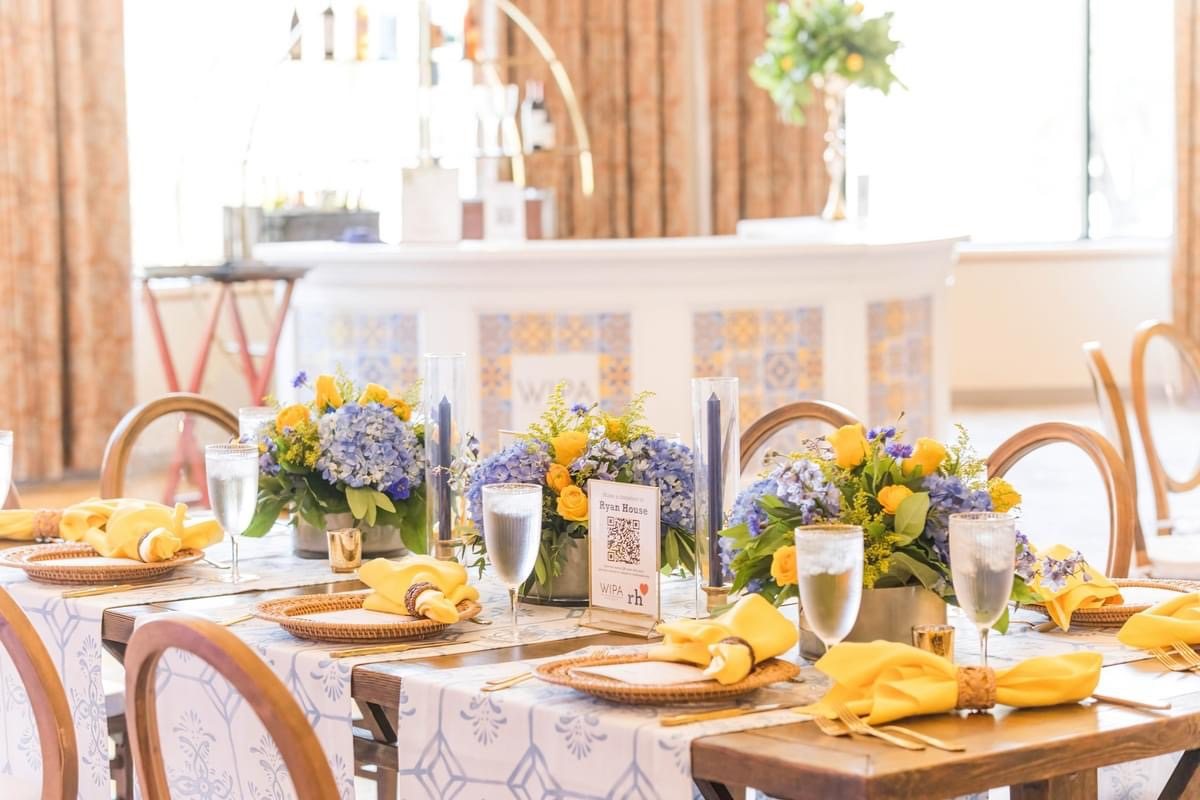 Long table with hydrangea florals, Ryan House donation sign, and the tile-paneled WIPA bar