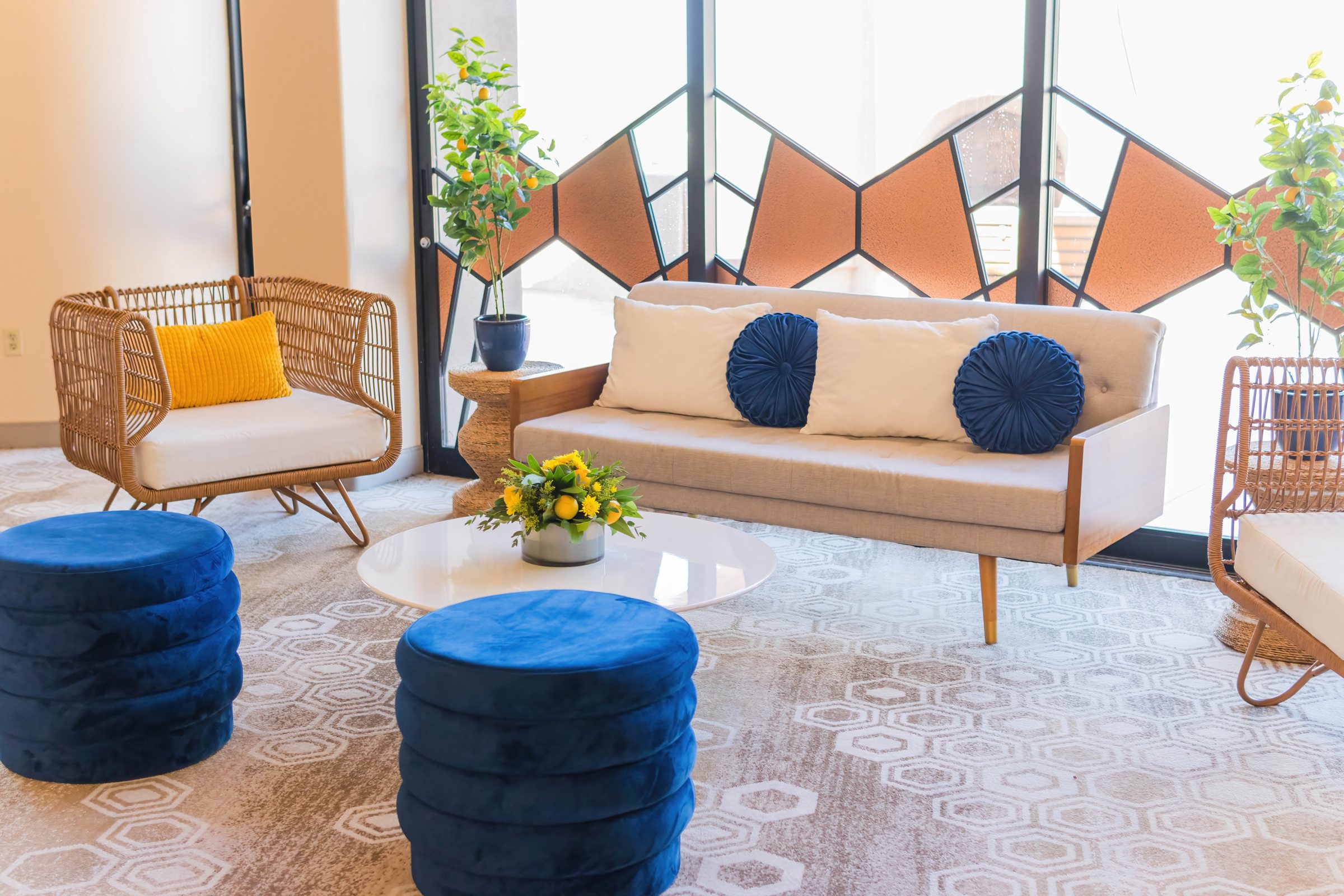 Lounge with rattan chairs, blue velvet poufs, and lemon trees