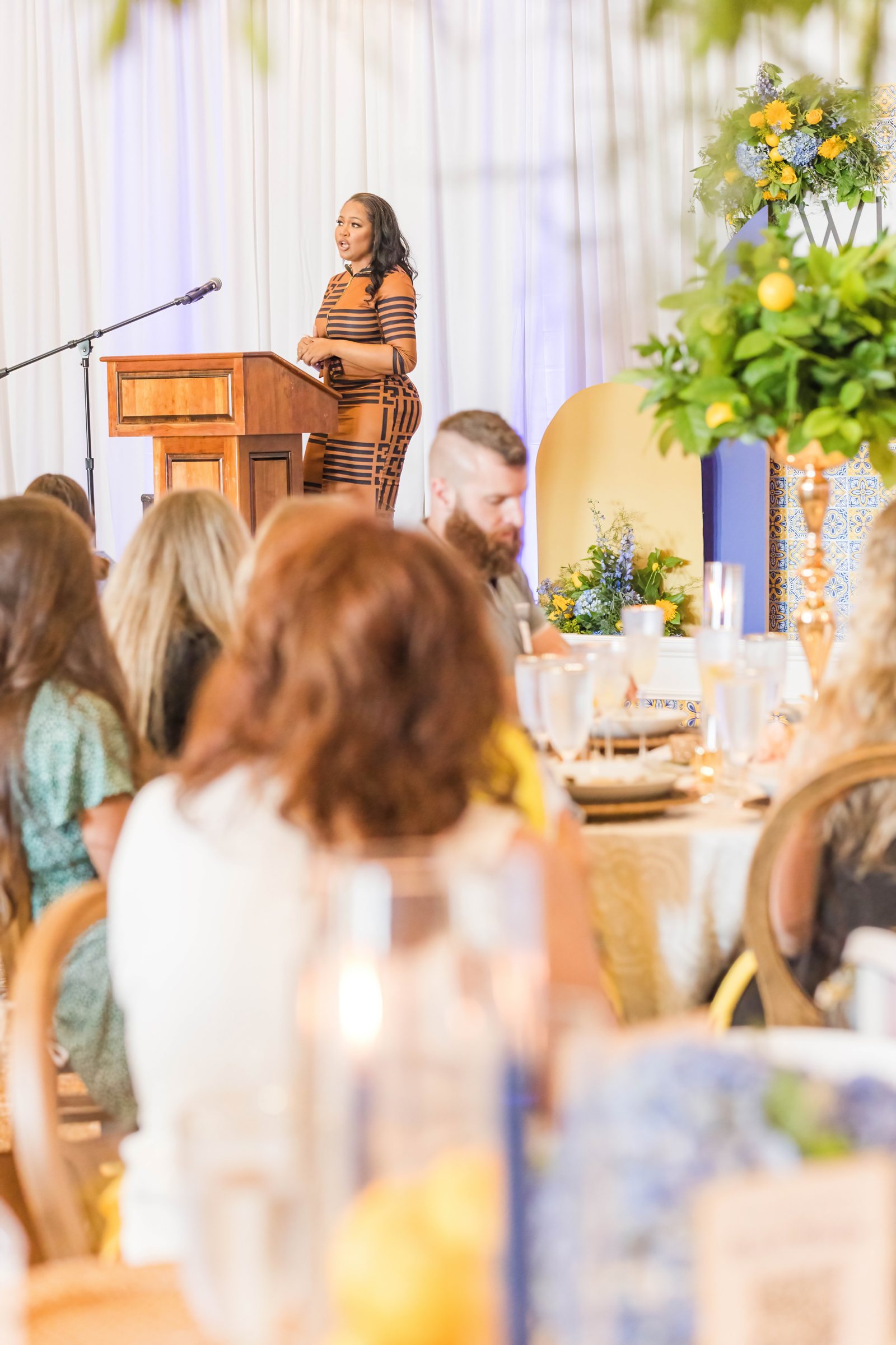 Featured speaker presenting to WIPA members beside the tiled stage backdrop