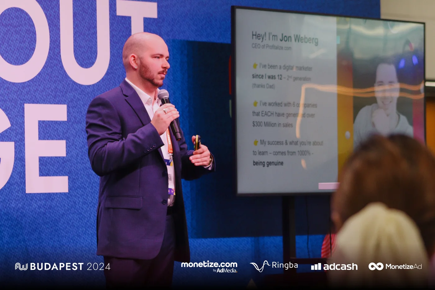 Jon Weberg on stage at AdWorld Budapest 2024 in front of a slide about companies that each generated over $300 million in sales
