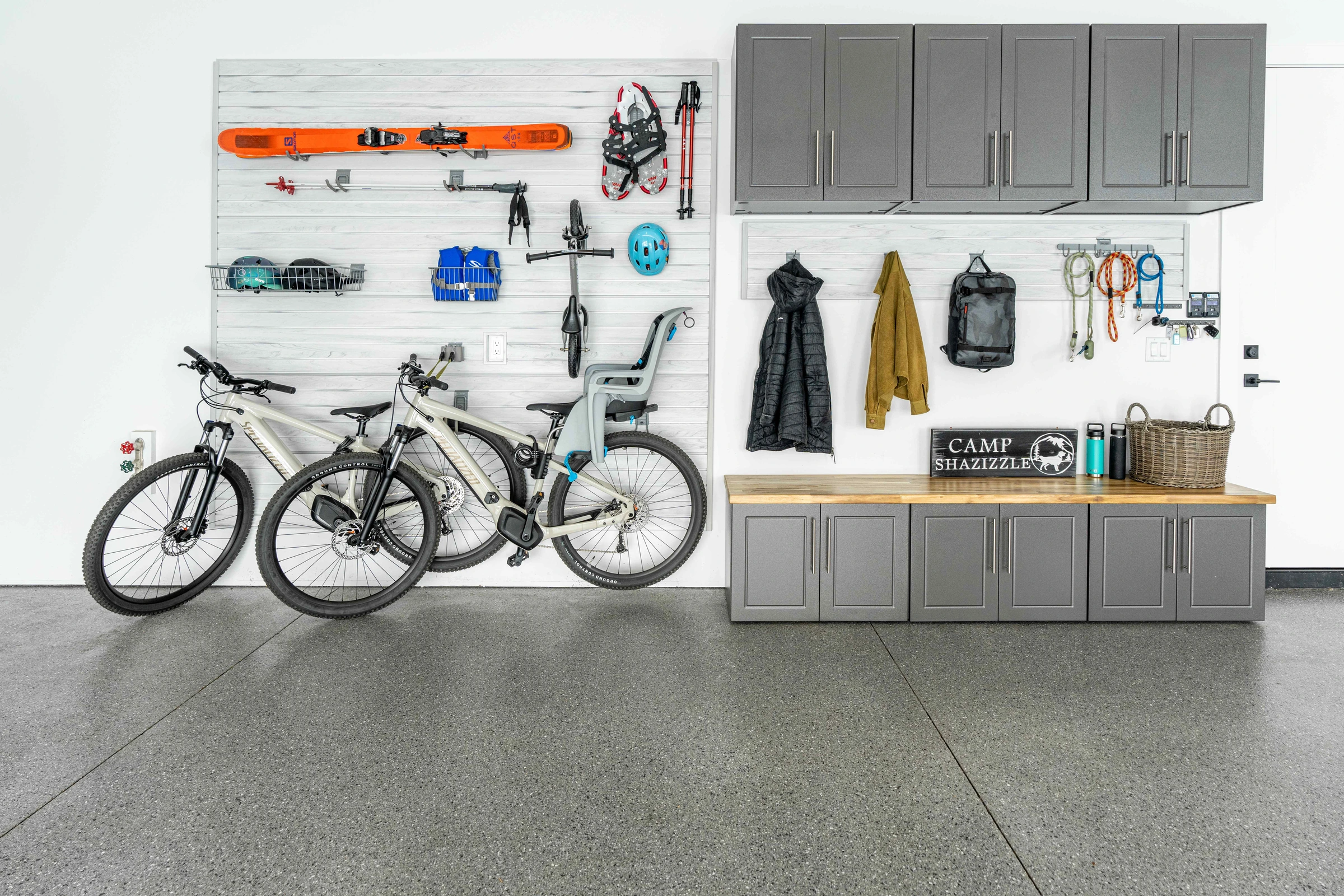 Custom gray garage cabinets with slatwall organization and wall-mounted bike and ski storage