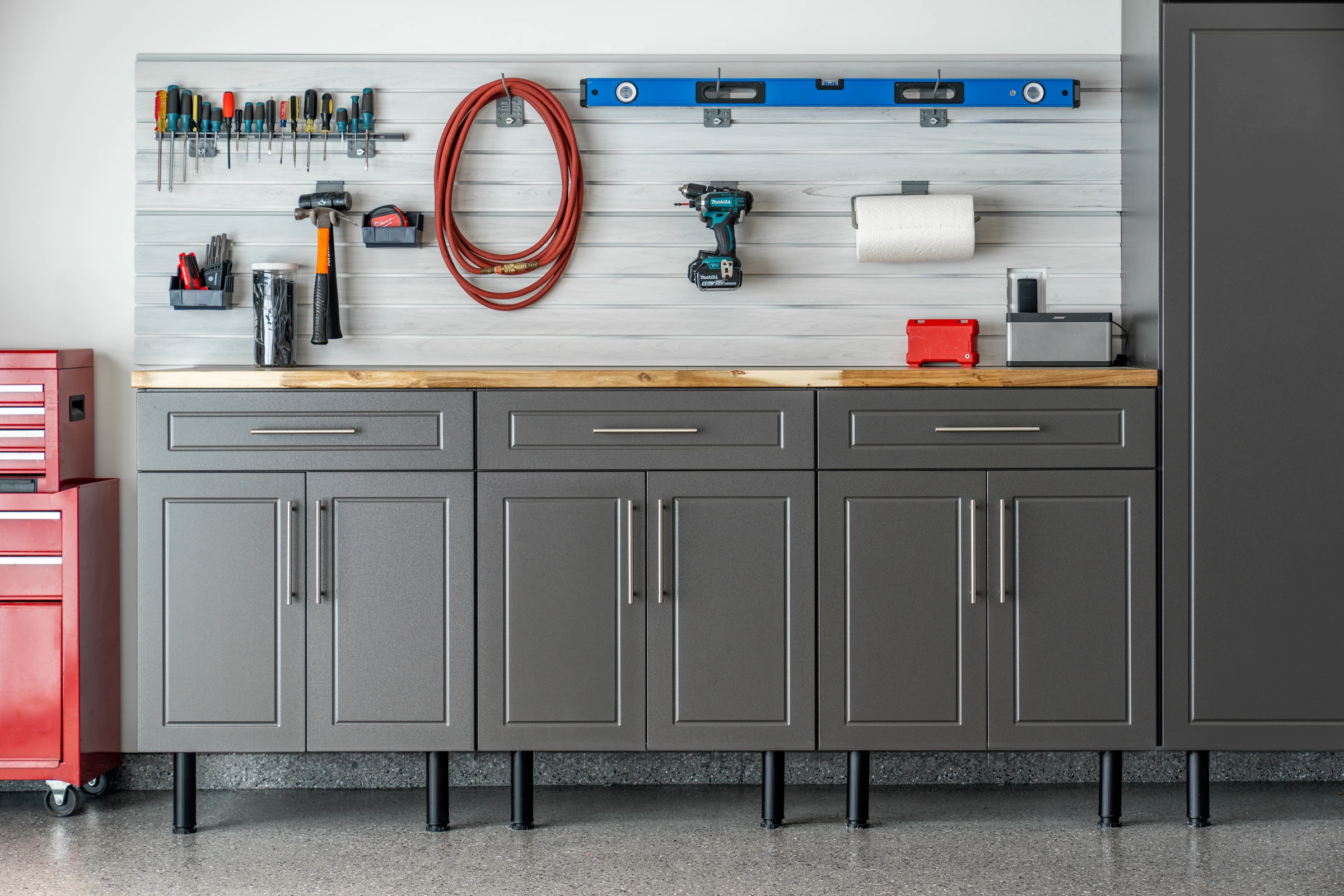 Custom charcoal garage cabinets with butcher block workbench, slatwall tool organization, tall storage cabinet, and premium polyaspartic garage floor installed by Garage Titan in Boise, Idaho.