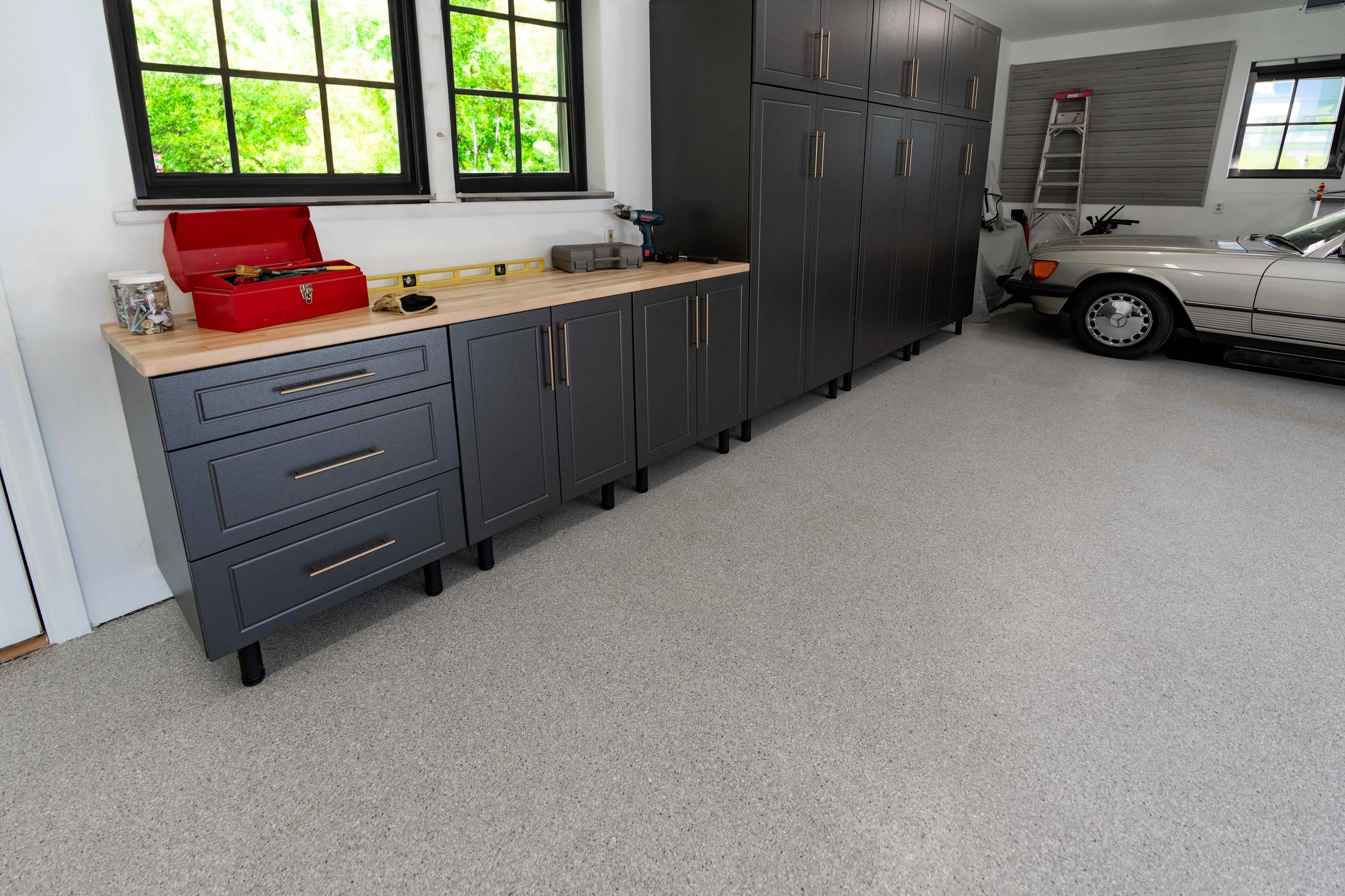 Custom charcoal garage cabinets with butcher block workbench, full-height storage cabinets, slatwall organization system, and polyaspartic garage floor coating installed by Garage Titan in Boise, Idaho.