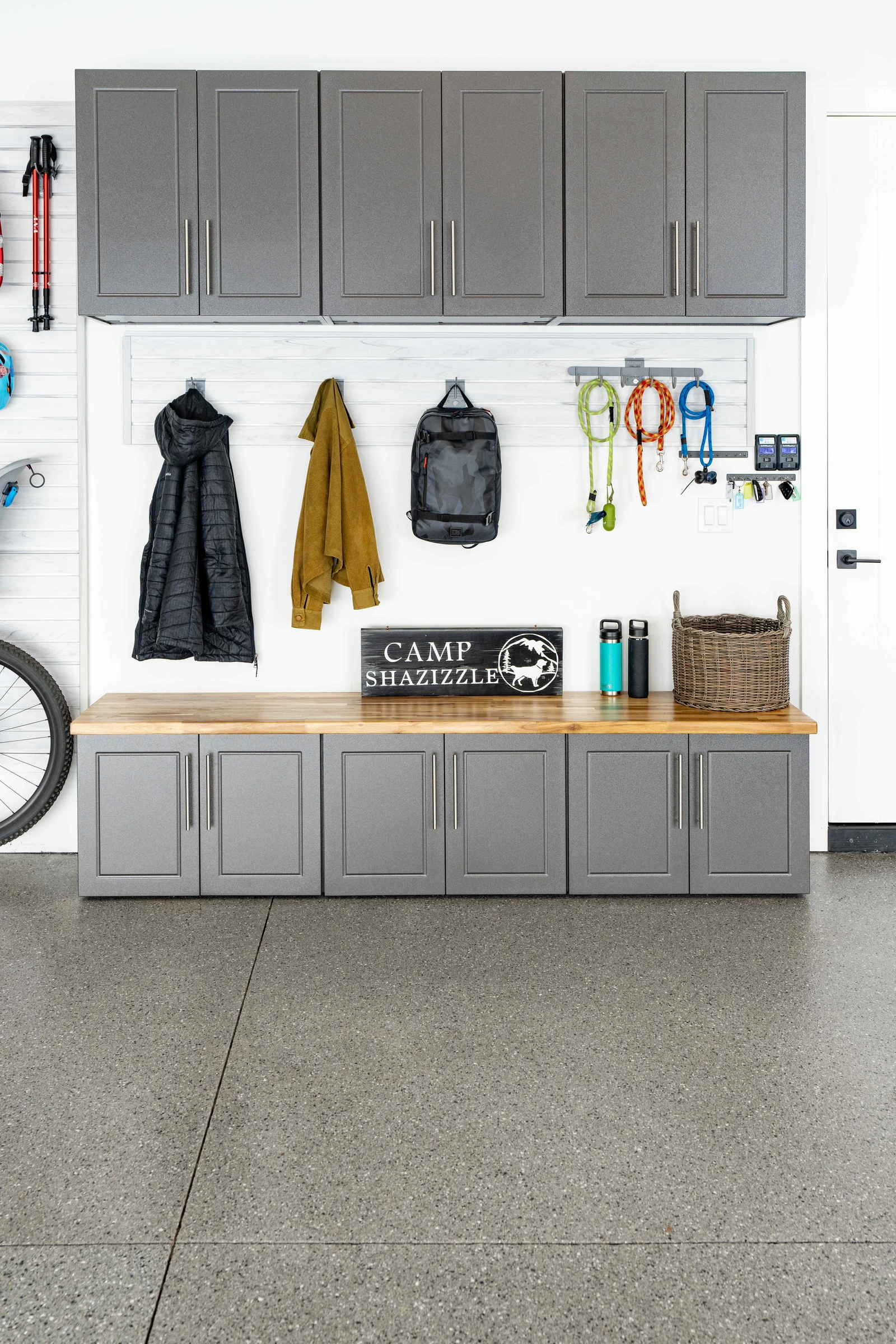 Custom gray garage cabinets with butcher block bench, upper storage cabinets, slatwall organization, and mudroom entry storage installed by Garage Titan in Boise, Idaho.
