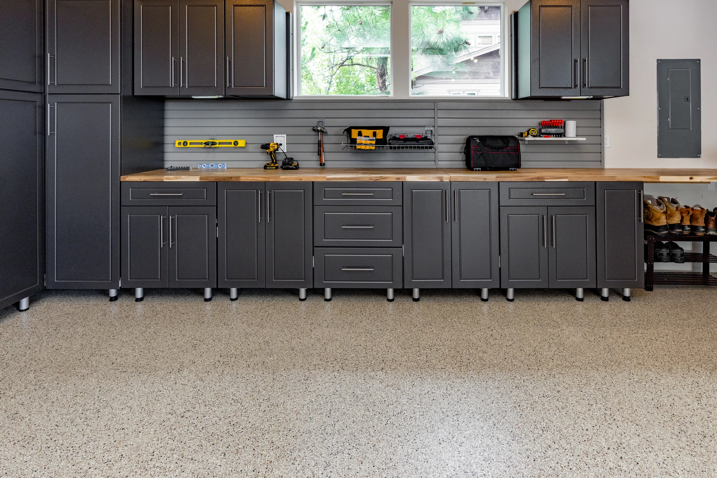 Custom charcoal garage cabinets with butcher block workbench, slatwall organization system, upper storage cabinets, and polyaspartic garage floor installed by Garage Titan in Boise, Idaho.
