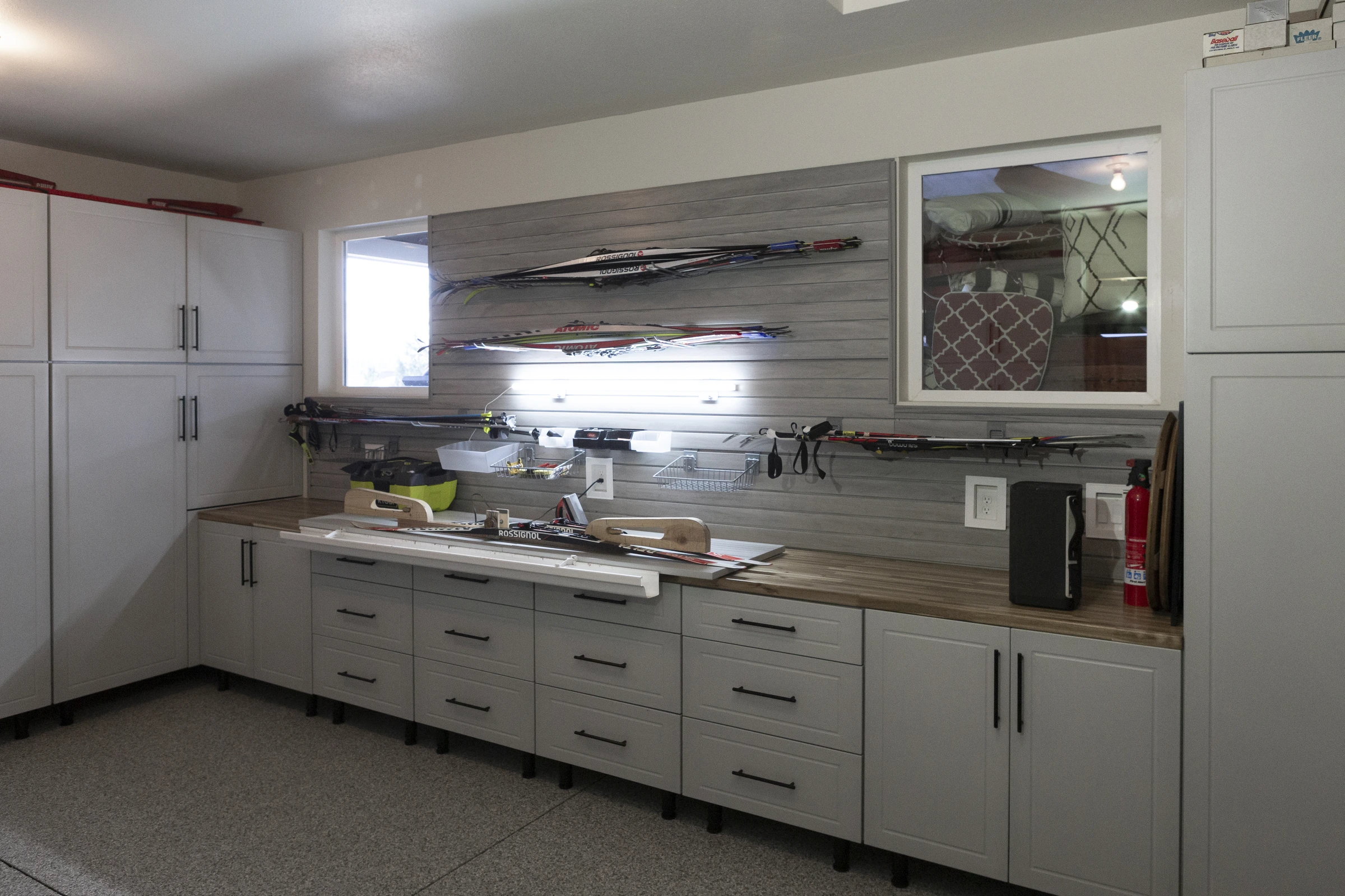 Custom light gray garage cabinets with butcher block workbench, slatwall ski storage system, and integrated lighting installed by Garage Titan in Boise, Idaho
