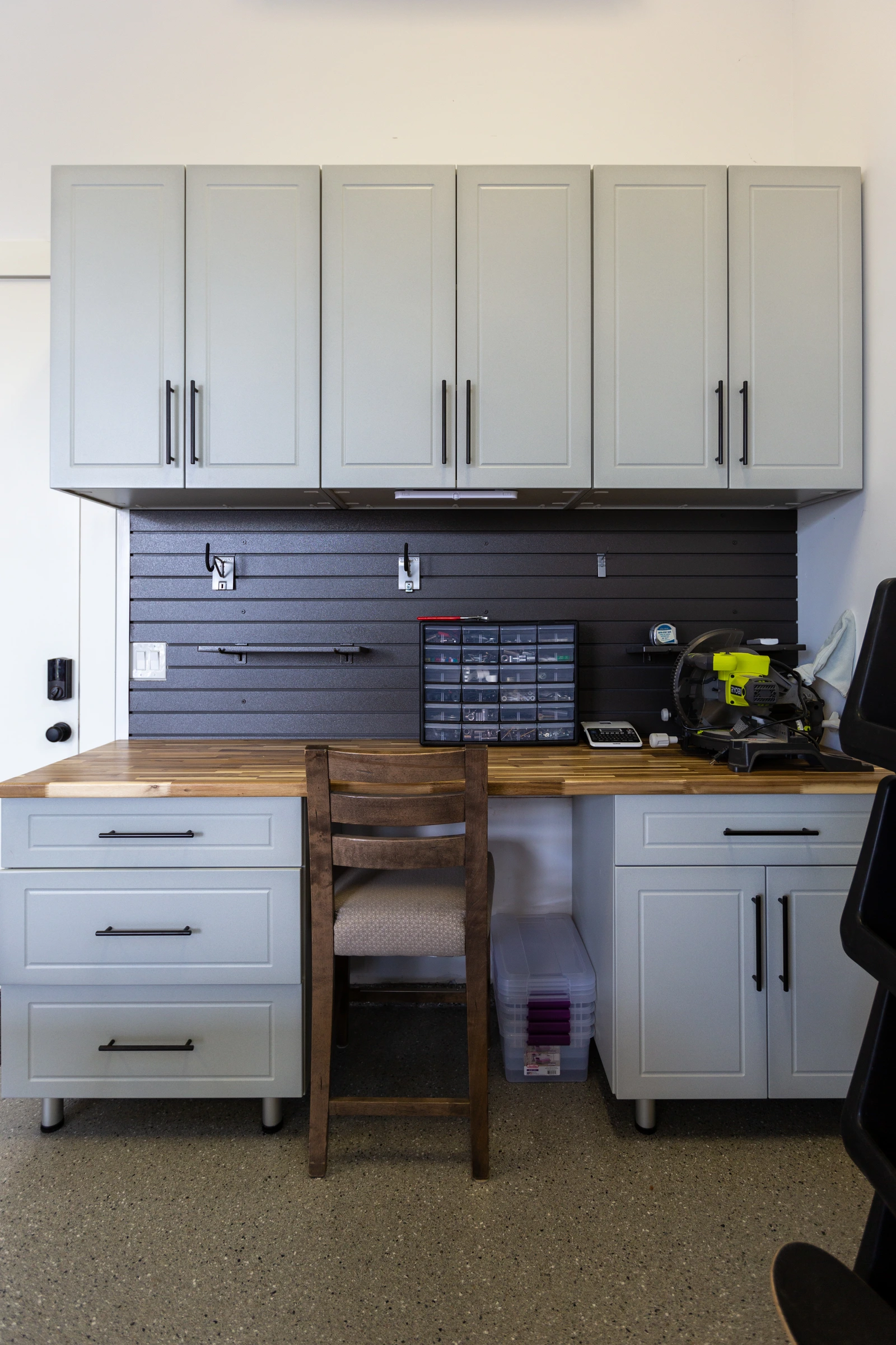 Custom white garage cabinets with butcher block workstation, black slatwall organization system, upper storage cabinets, and durable polyaspartic garage floor installed by Garage Titan in Boise, Idaho.