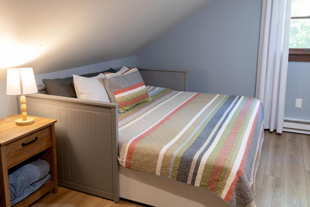 The kids will fight over the trundle room — colorful quilts, sloped ceiling, and the feeling of a private hideout.
