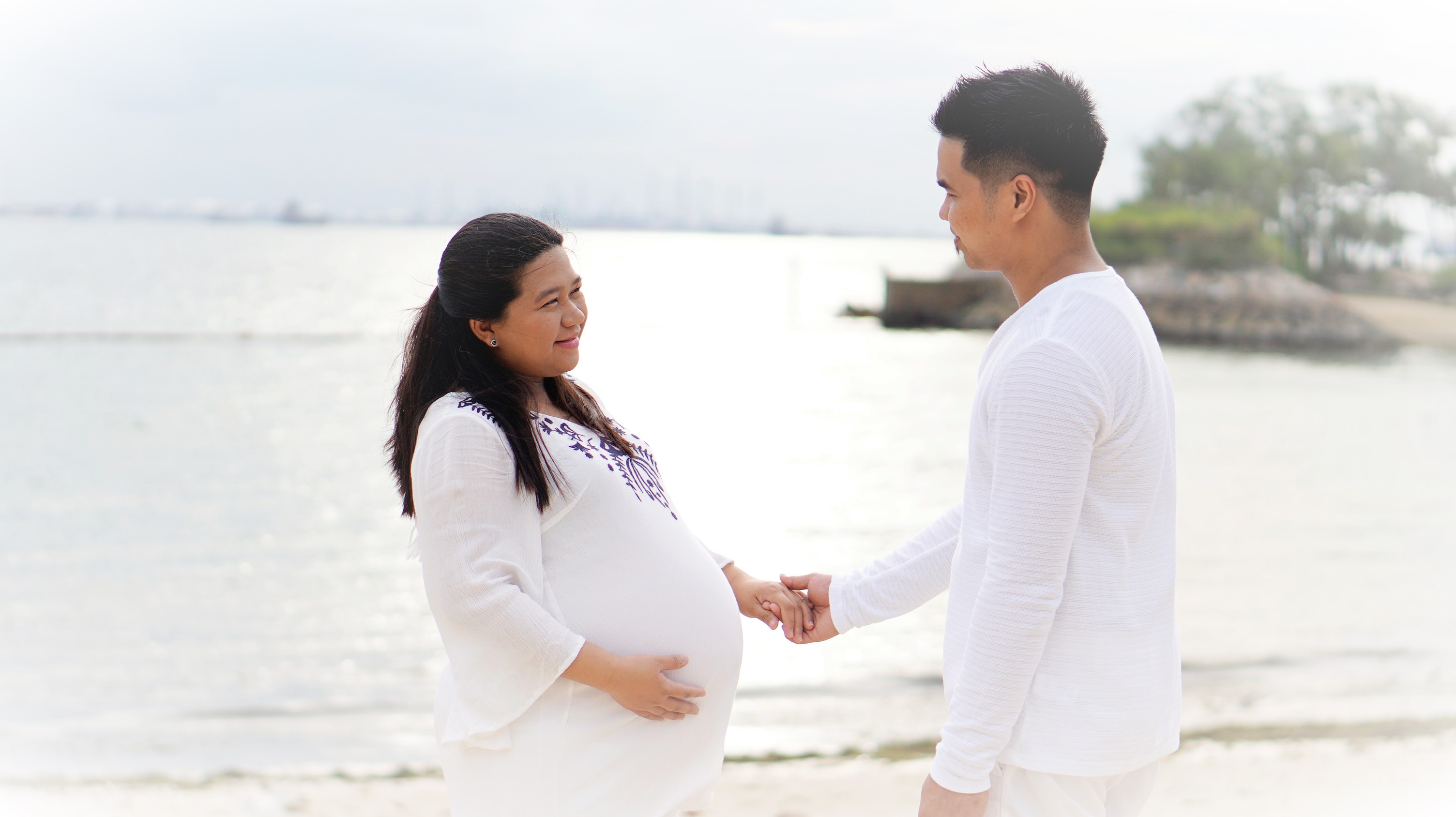 An expectant couple photographed by the water