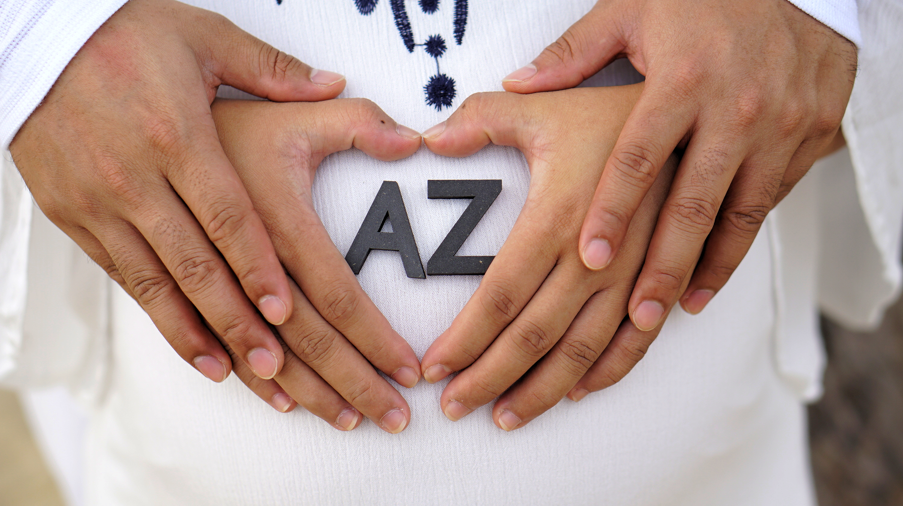 Two pairs of hands forming a heart over the bump