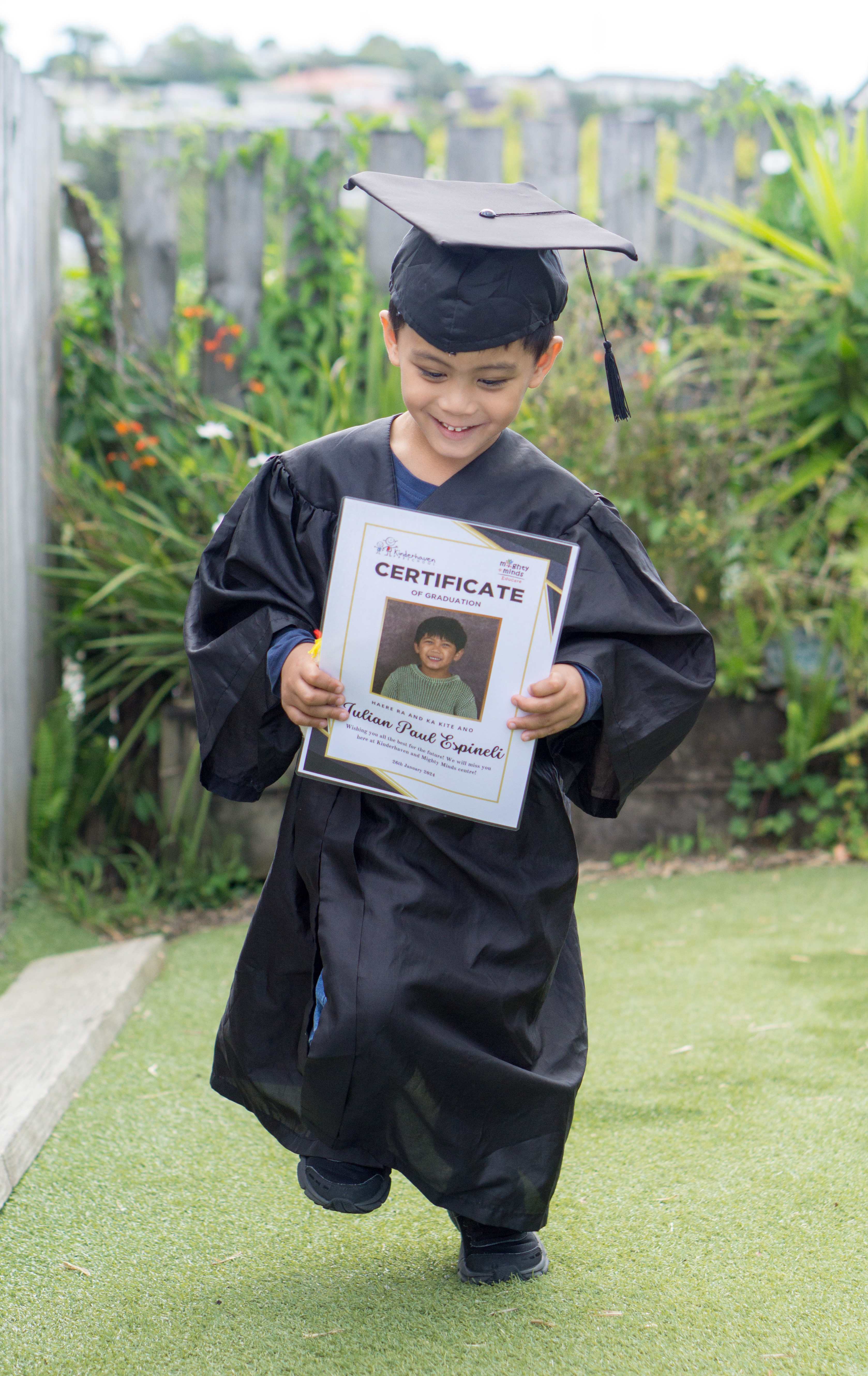 A boy in cap and gown holding his certificate
