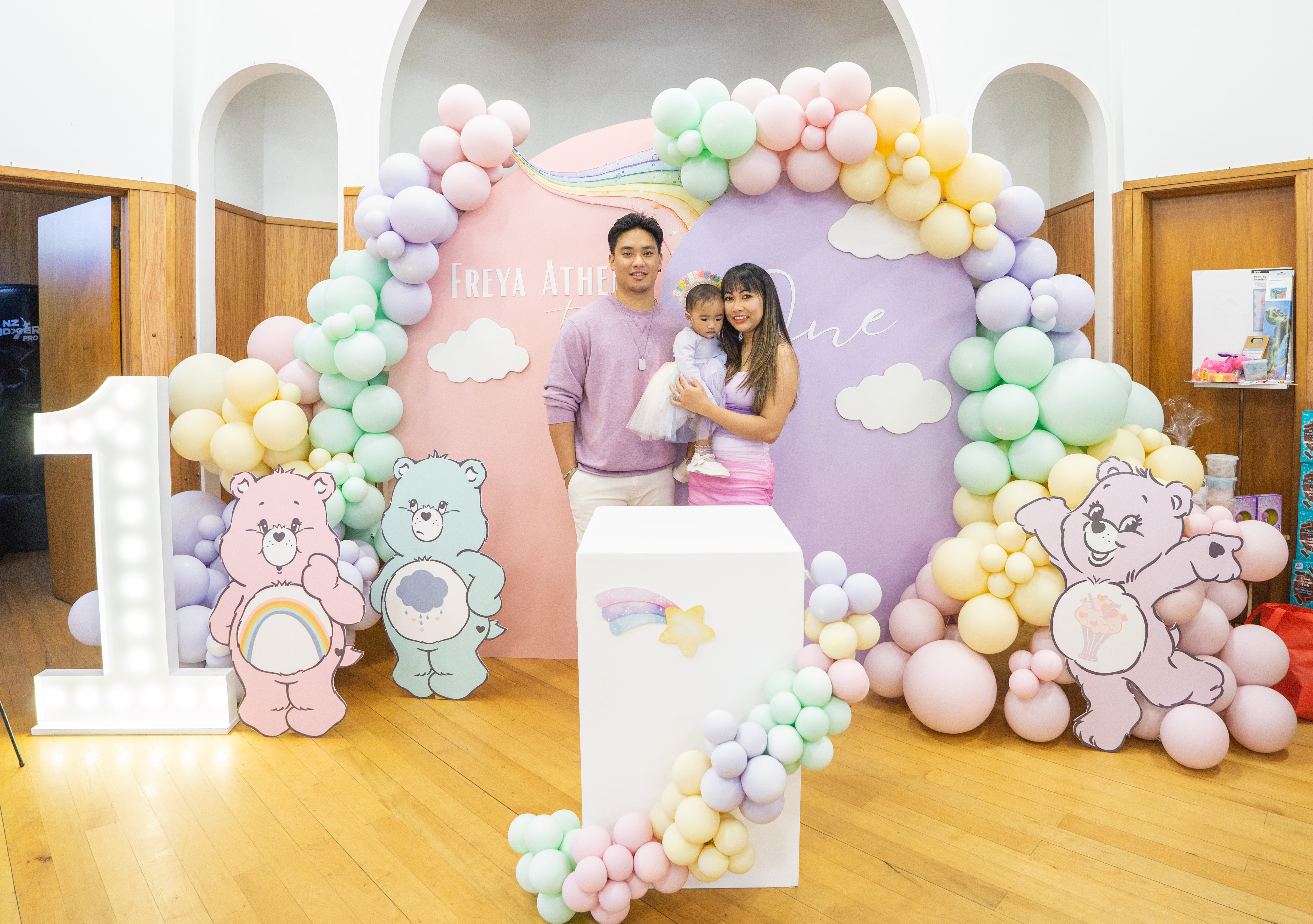 A first birthday table set under a pastel balloon arch