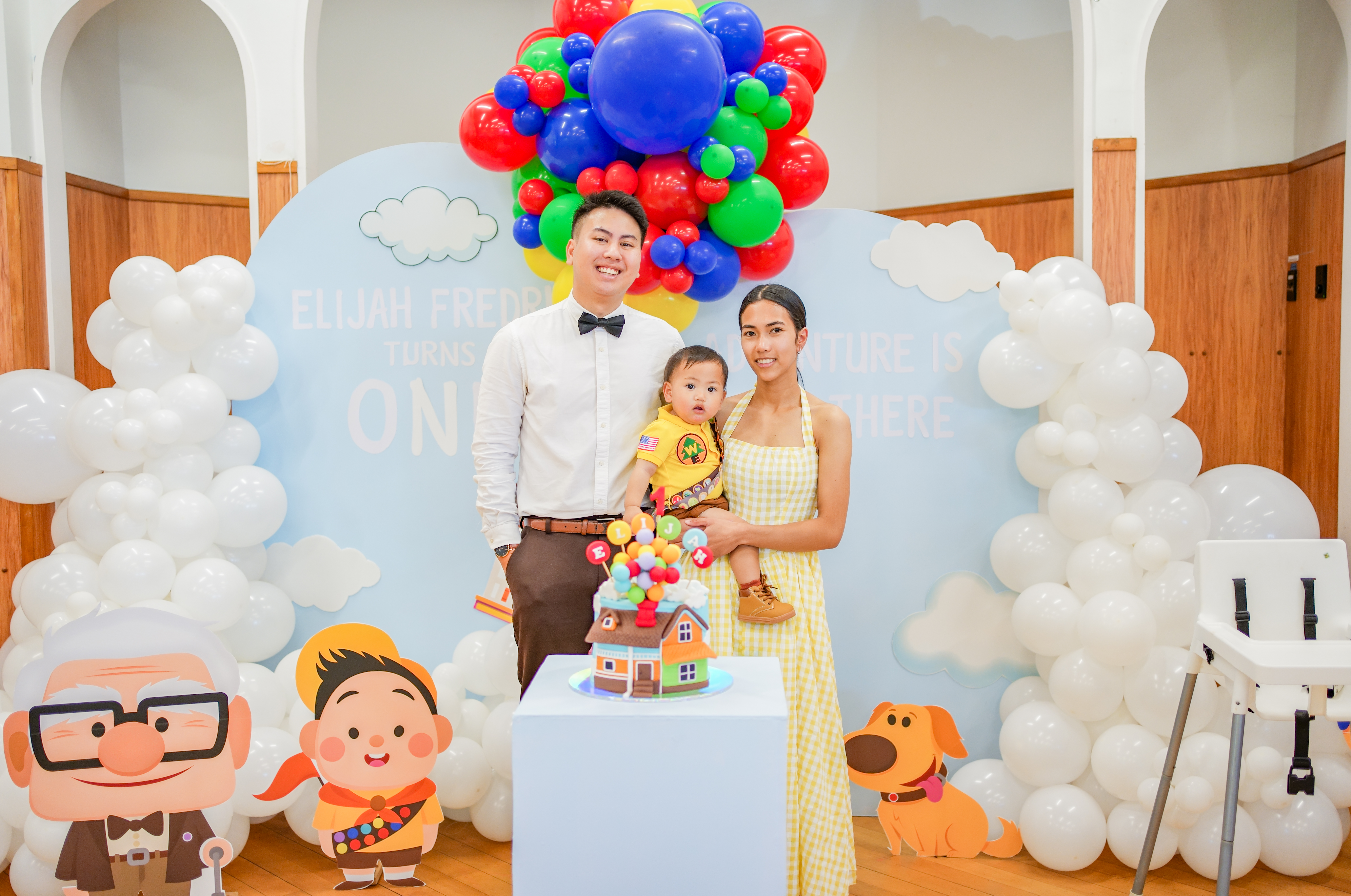 A first birthday photographed under a balloon arch