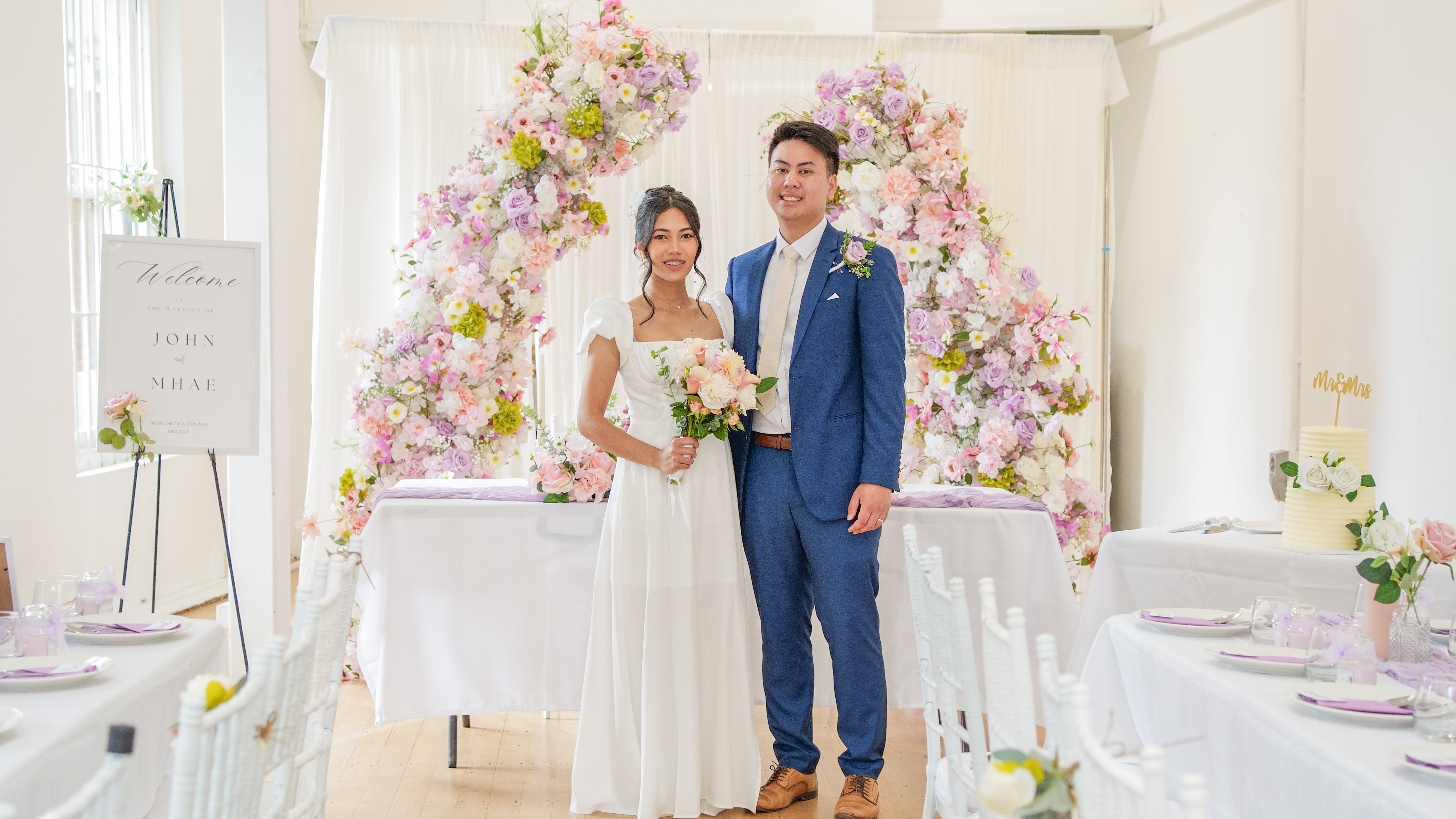 A couple photographed under a floral arch on their wedding day