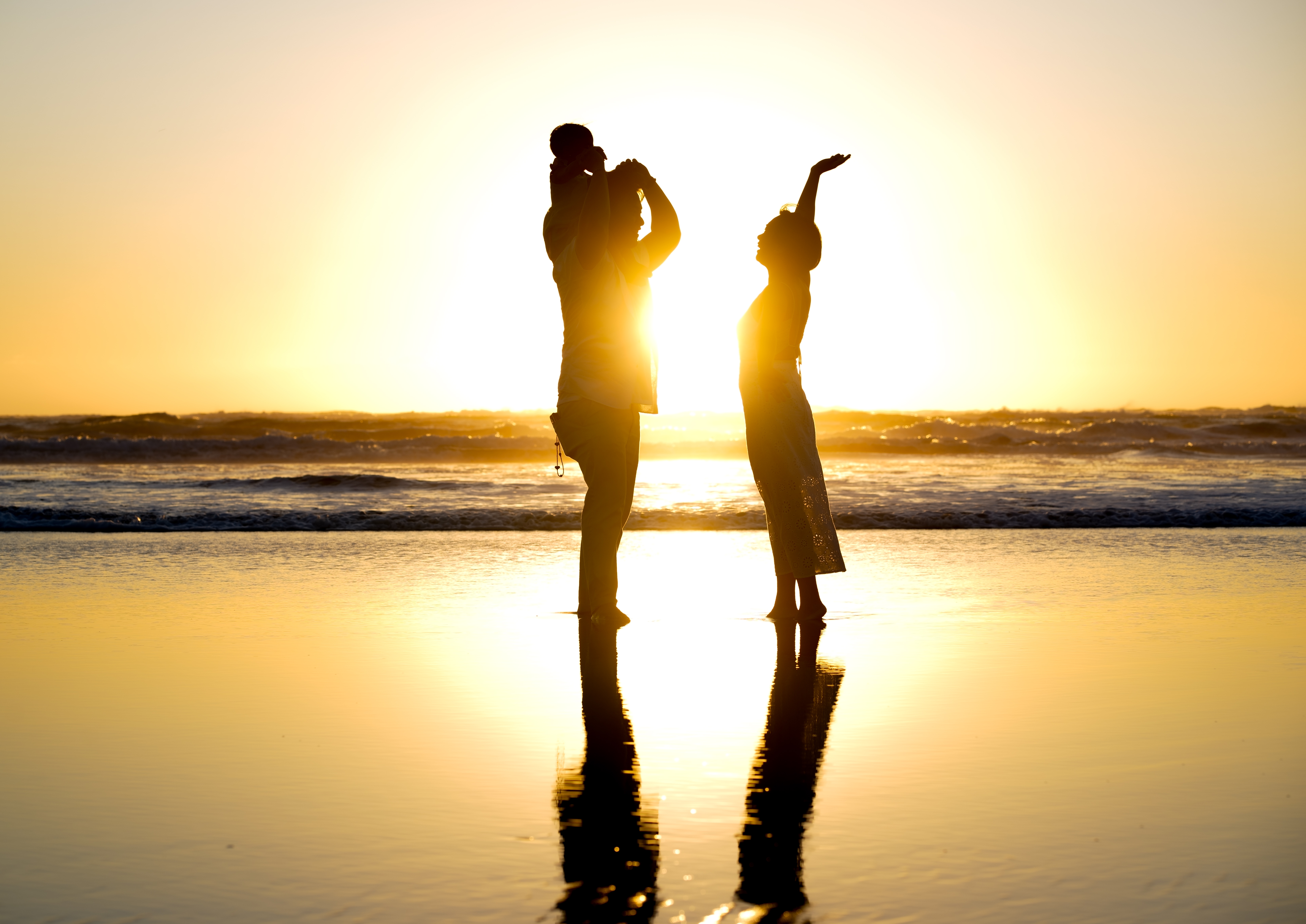 A family silhouetted against a golden sunset on the beach
