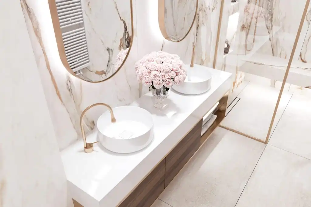 Walk-in glass shower with stone walls, gold hardware, and built-in niche lighting