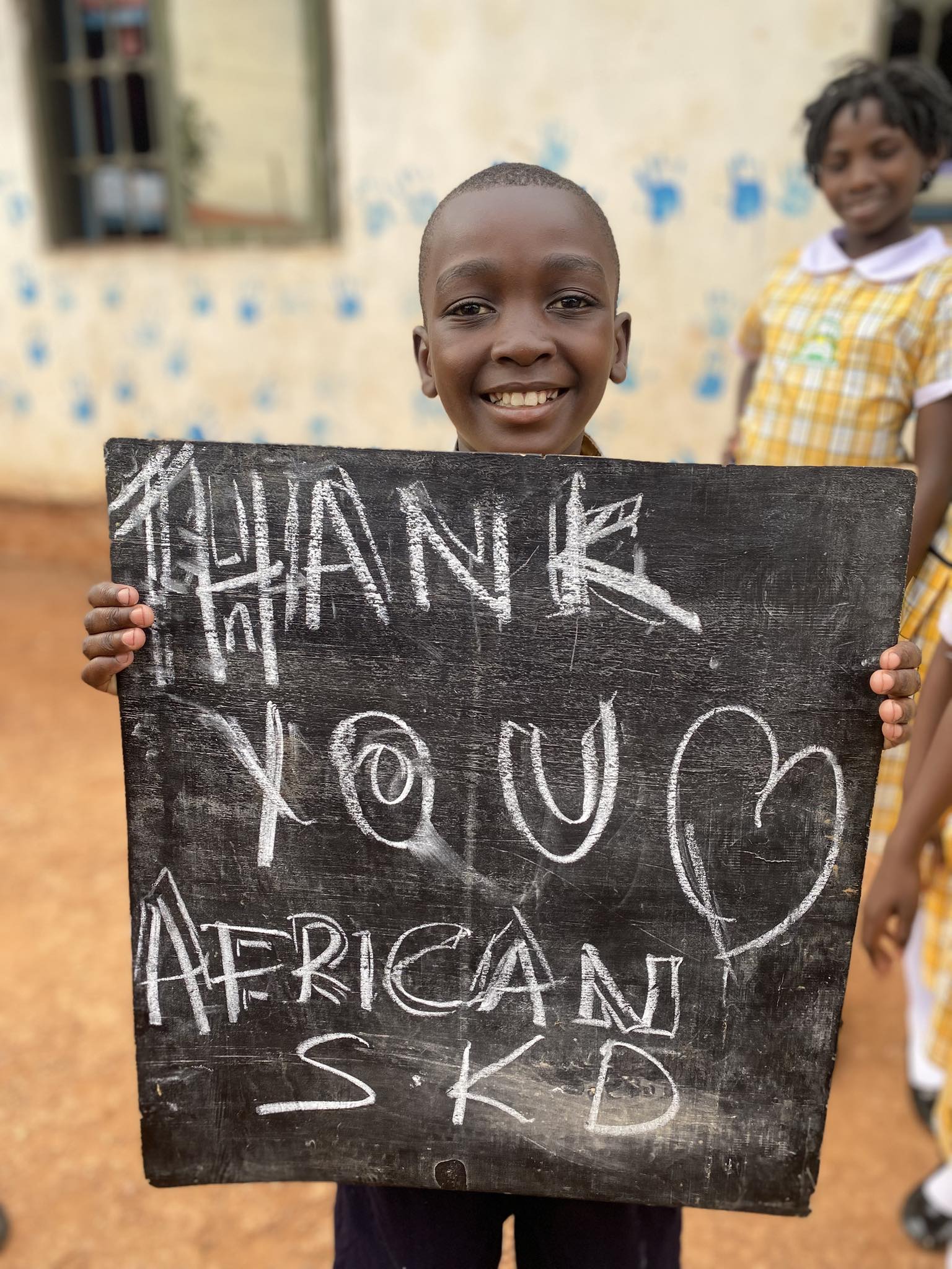 Child holding Thank You African SKD chalkboard sign