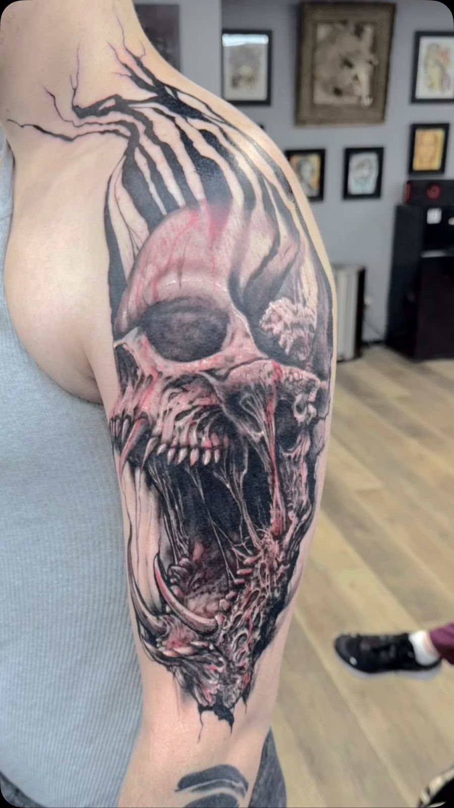Black-and-grey realistic skull with red accents covering the upper arm and shoulder