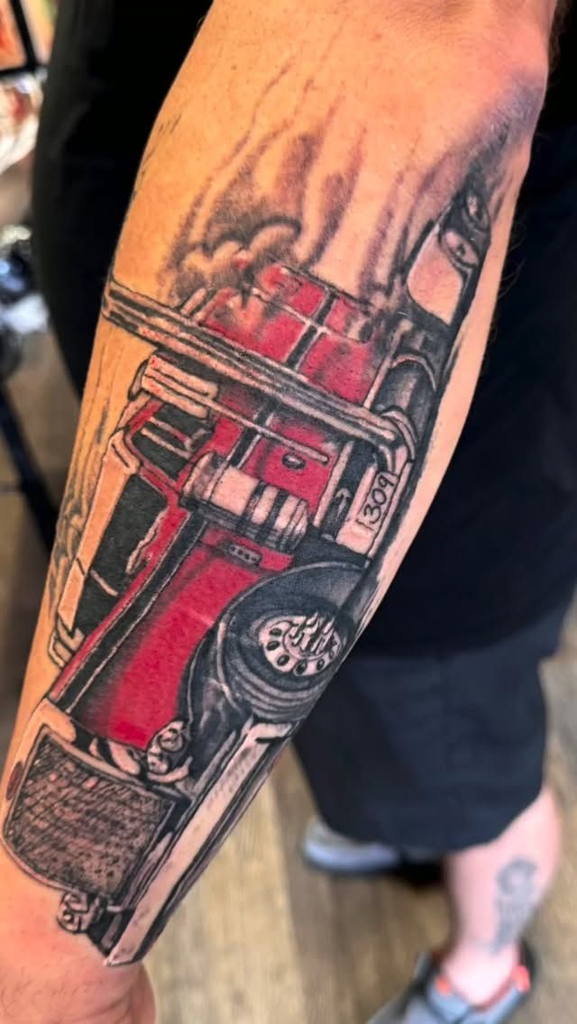Peterbilt semi truck tattoo in black and grey with red on the forearm