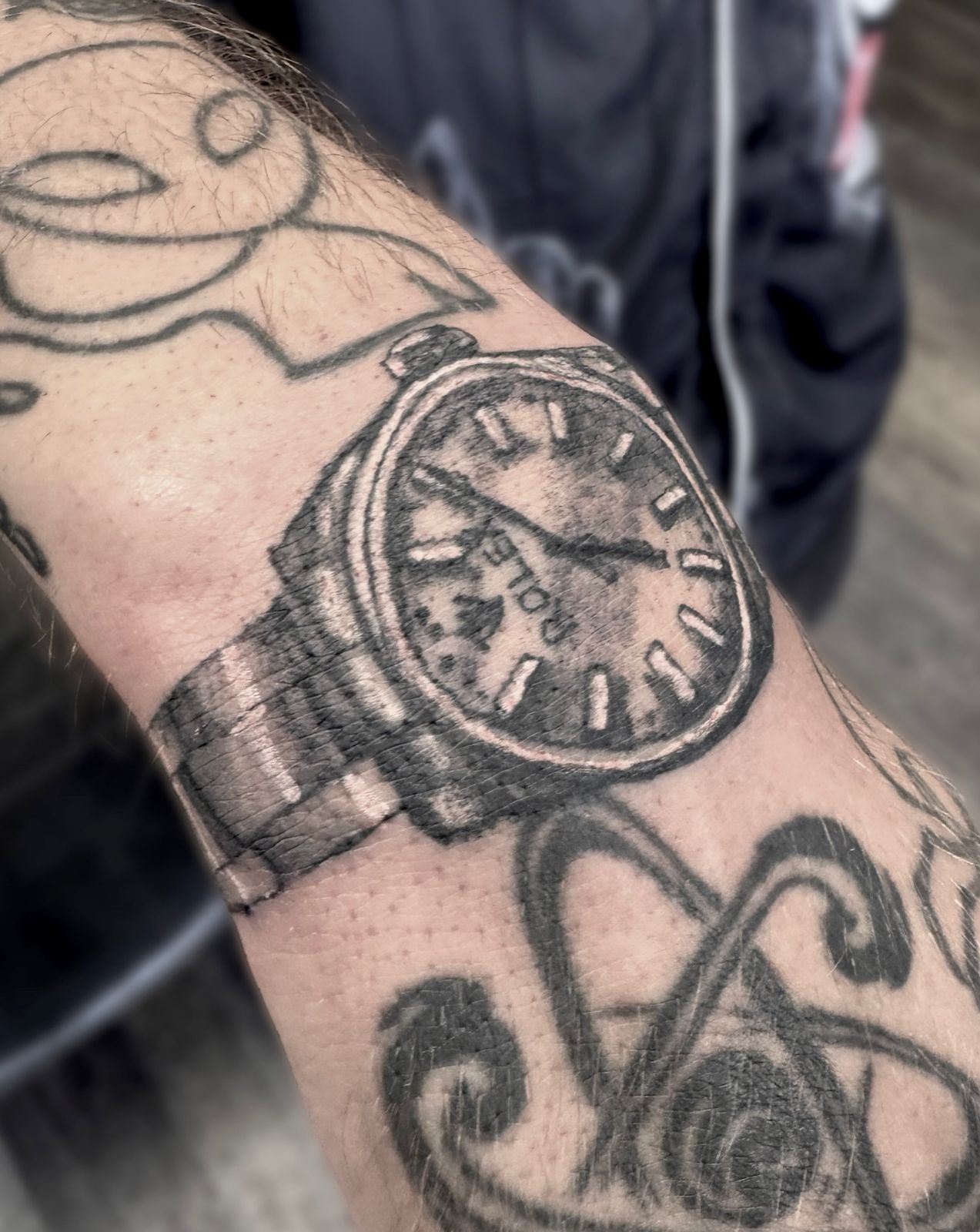 Black-and-grey realistic Rolex wristwatch tattoo on the forearm
