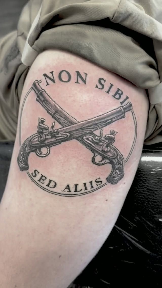 Military crossed-pistols emblem with NON SIBI SED ALIIS lettering on the upper arm