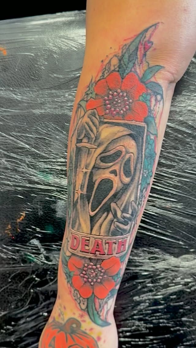 Color Ghostface tattoo with red flowers and DEATH banner on the forearm