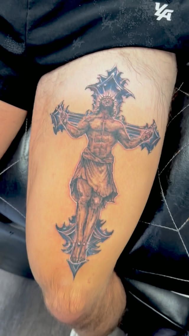 Color crucifix tattoo on the upper arm