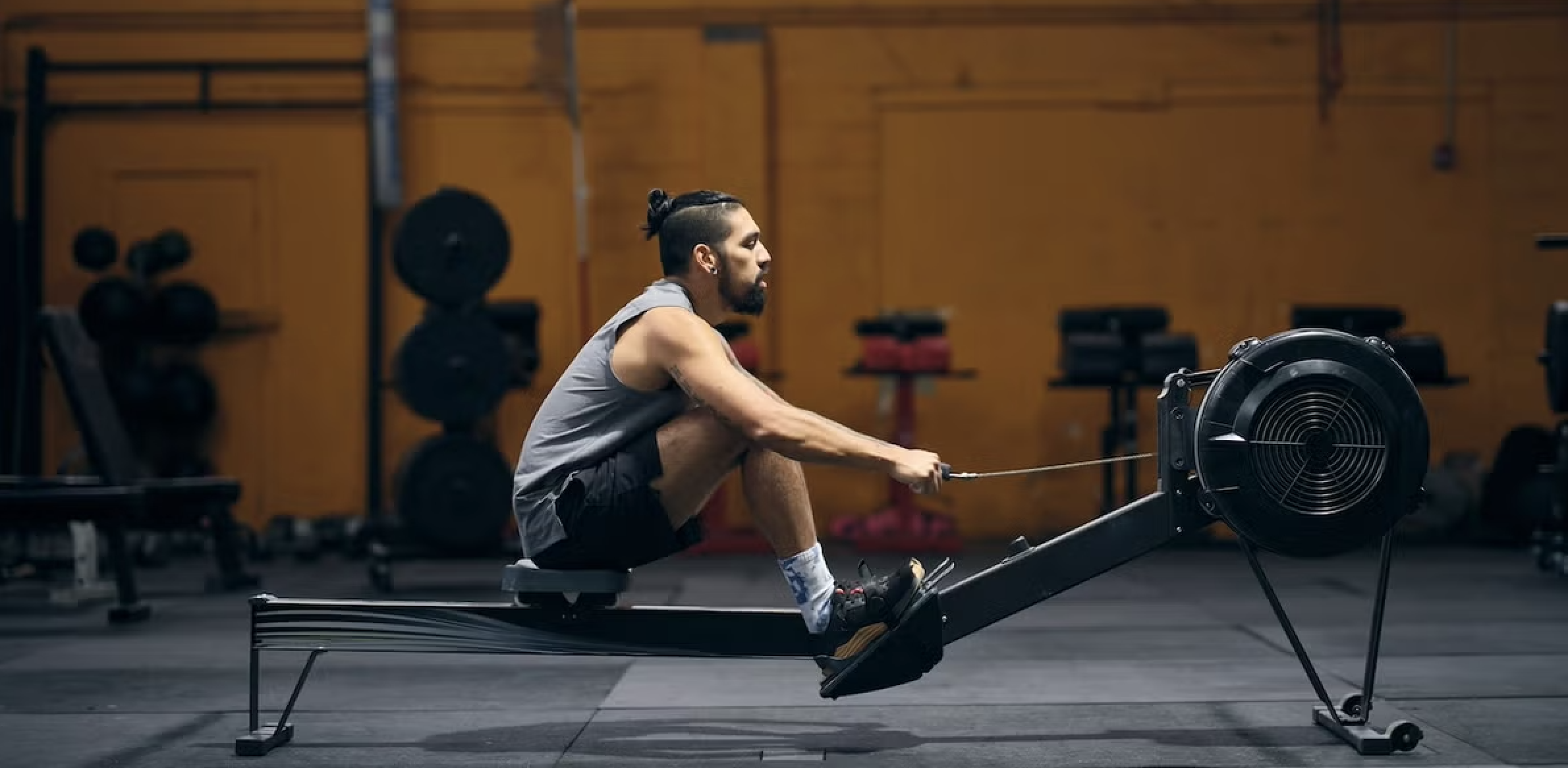 A man using an indoor rowing machine in a gym, highlighting correct body alignment for injury prevention. A man using an indoor rowing machine in a gym, highlighting correct body alignment for injury prevention.
