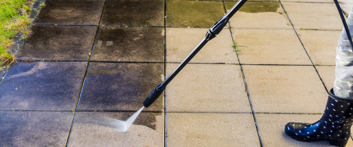 Pressure washing patio tiles to remove dirt, grime, and stains outdoors.