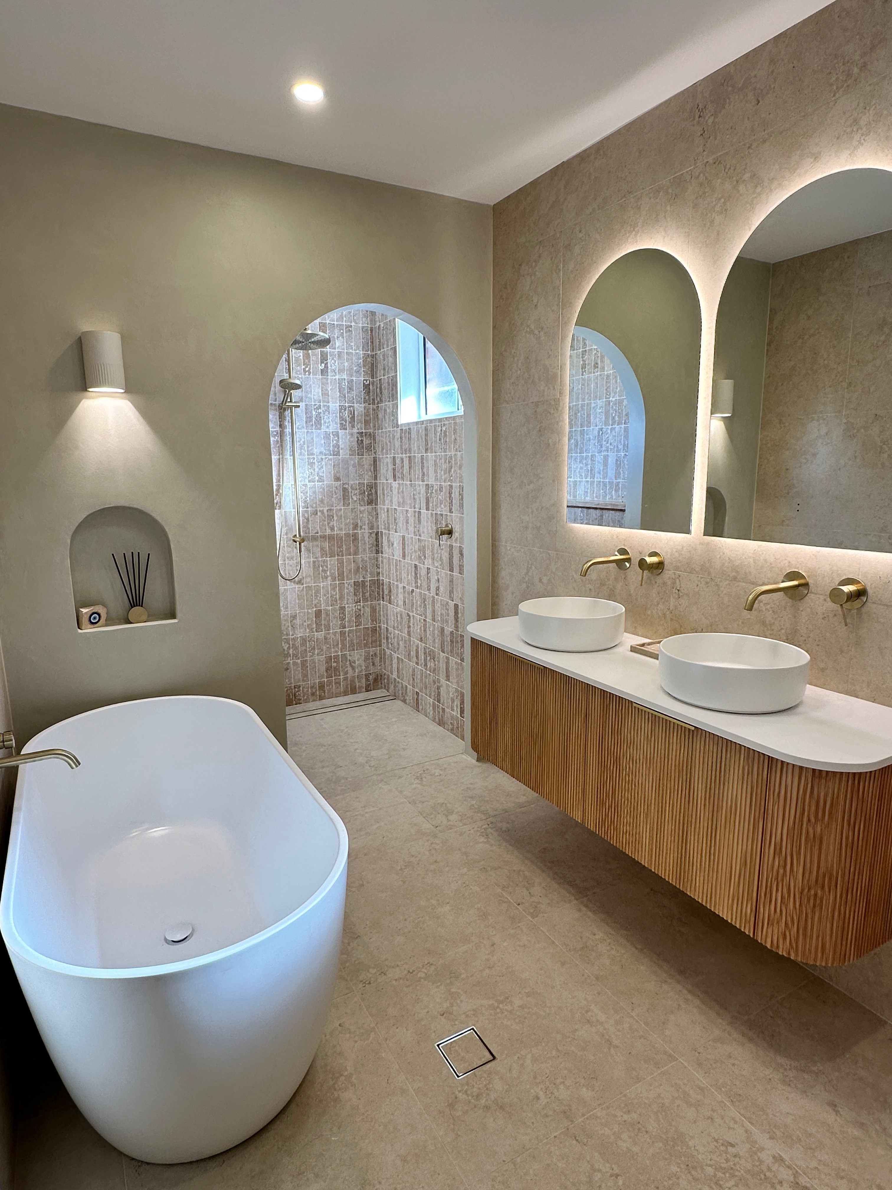 Finished bathroom with arched shower, freestanding bath and timber vanity
