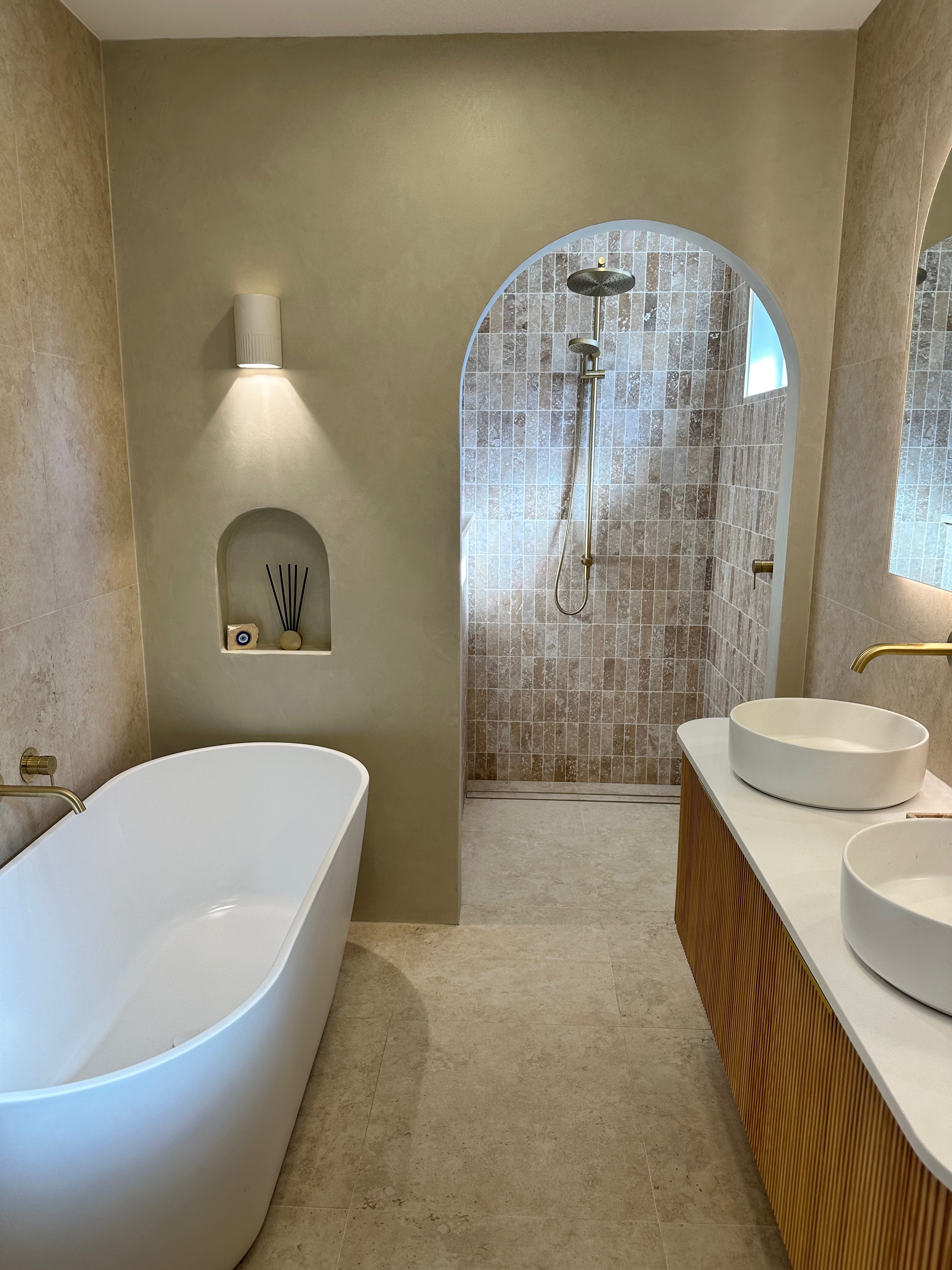 Finished bathroom with arched shower opening and freestanding bath