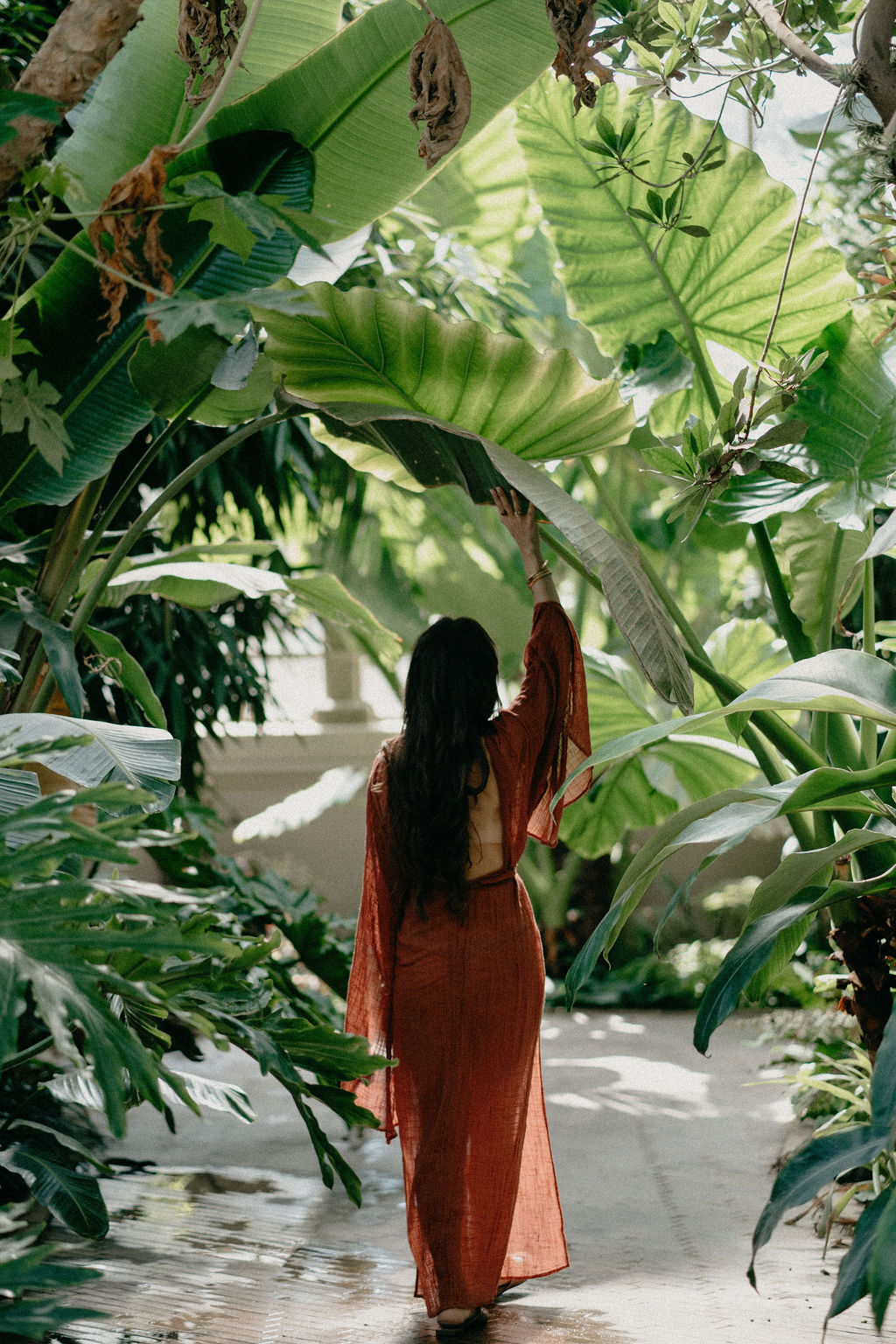 Mujer de espaldas entre plantas tropicales
