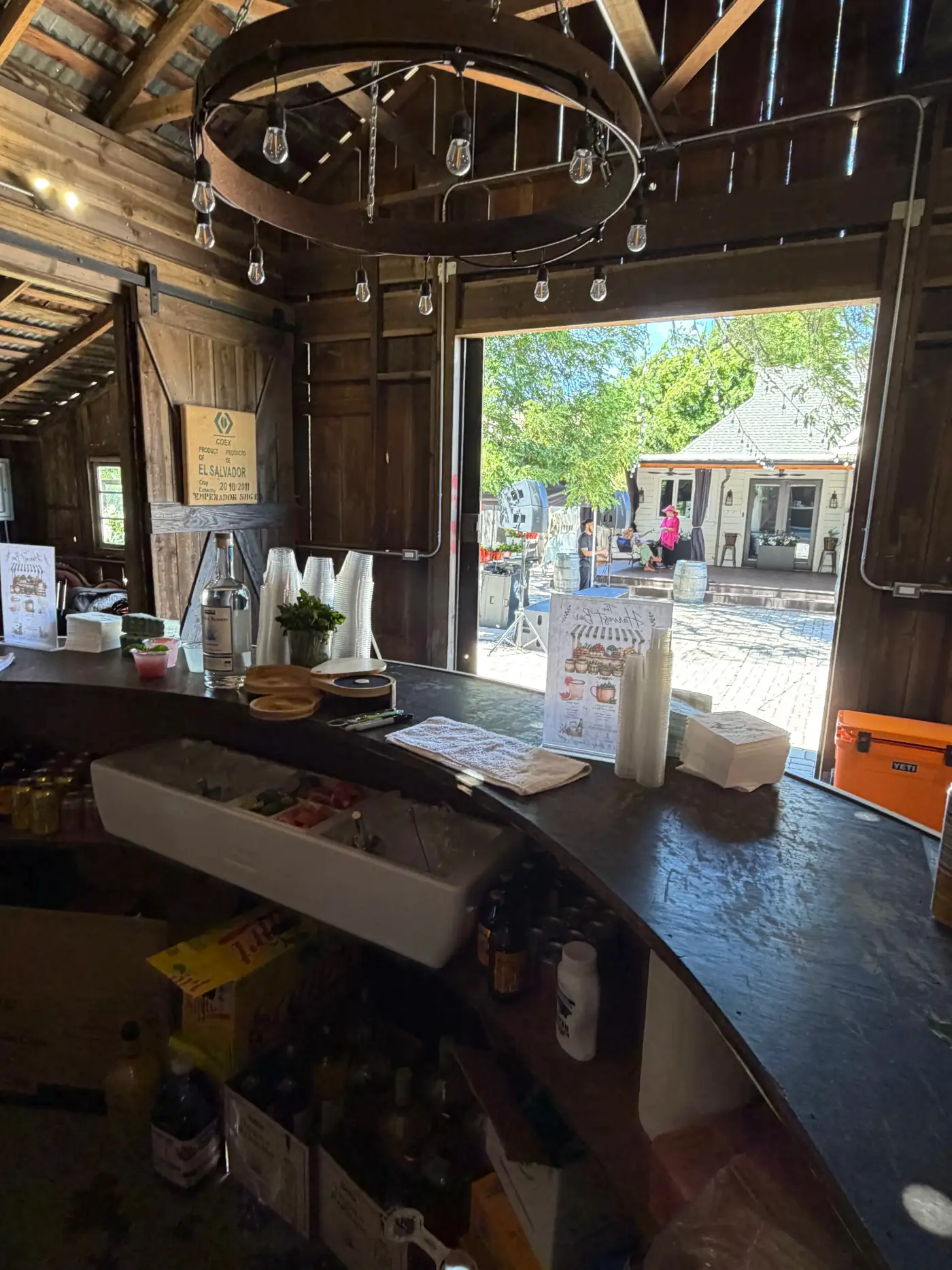 Behind the bar in a rustic barn venue, bottles and menu signage