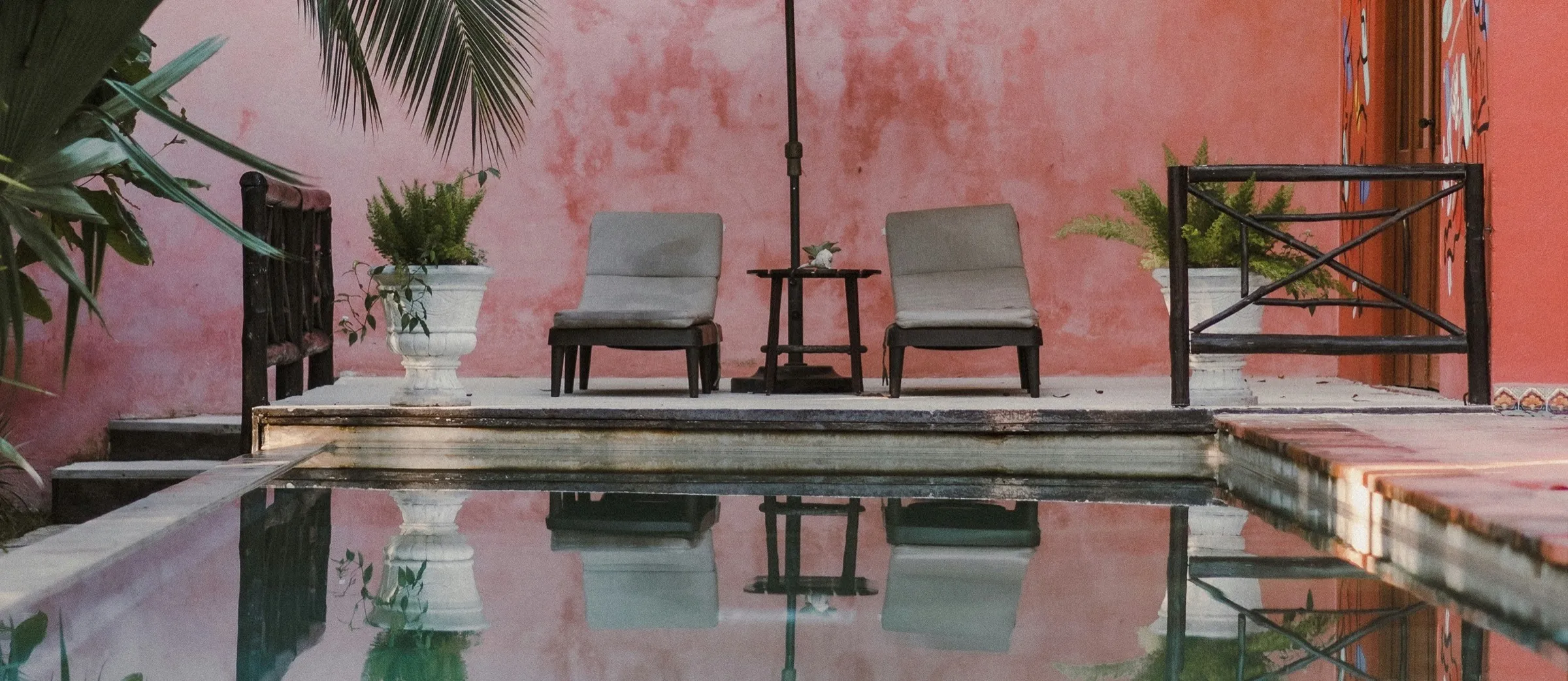 Patio de un hotel boutique con piscina y paredes terracota