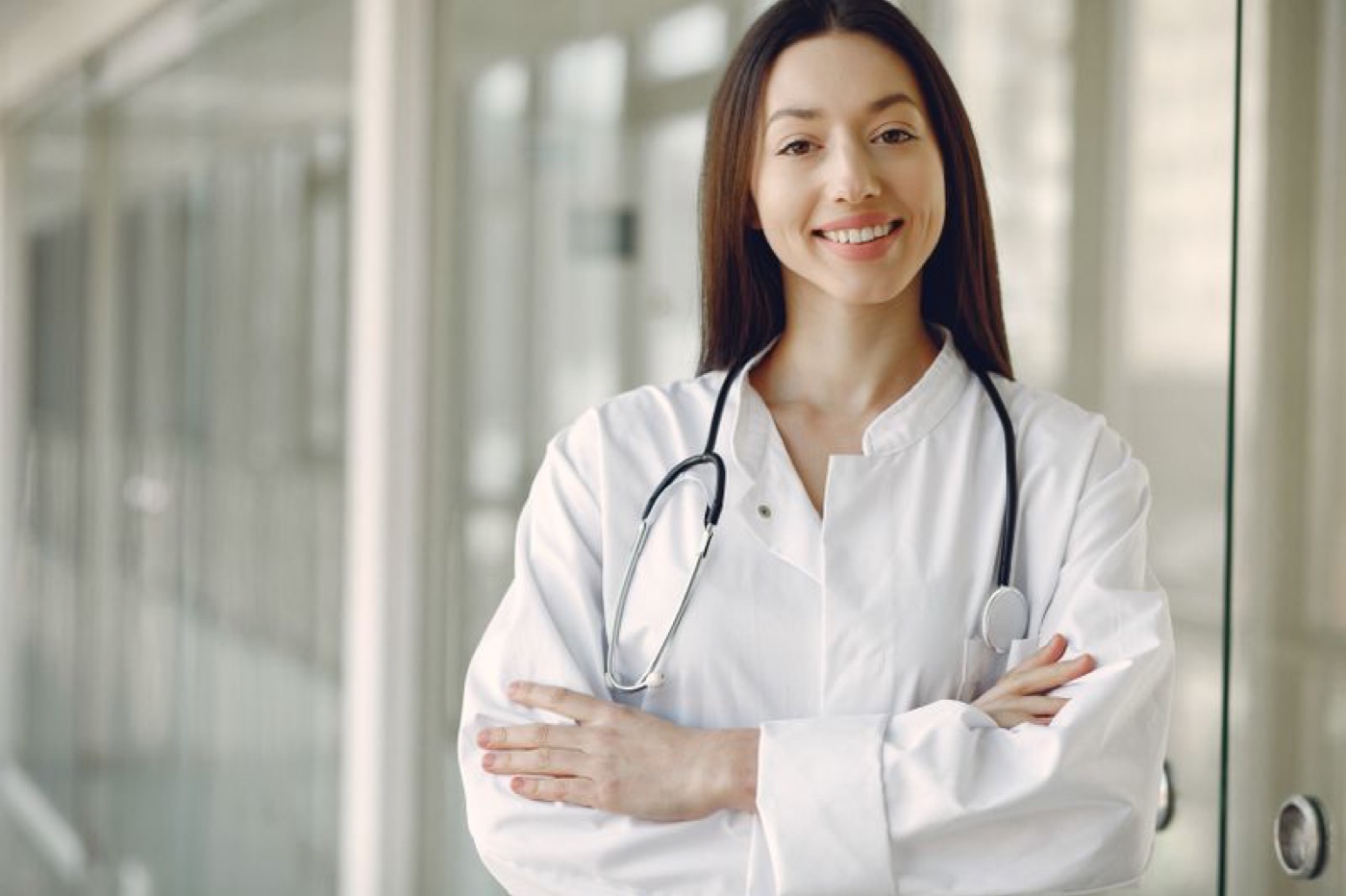 A physician in a white coat with a stethoscope, smiling — illustrative stock photo