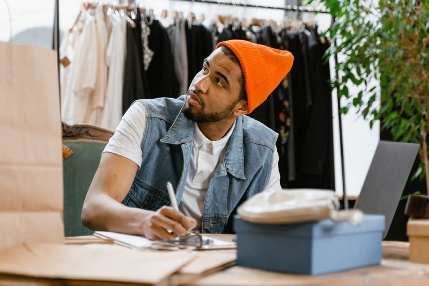 An apparel business owner packing an order at his laptop — illustrative stock photo