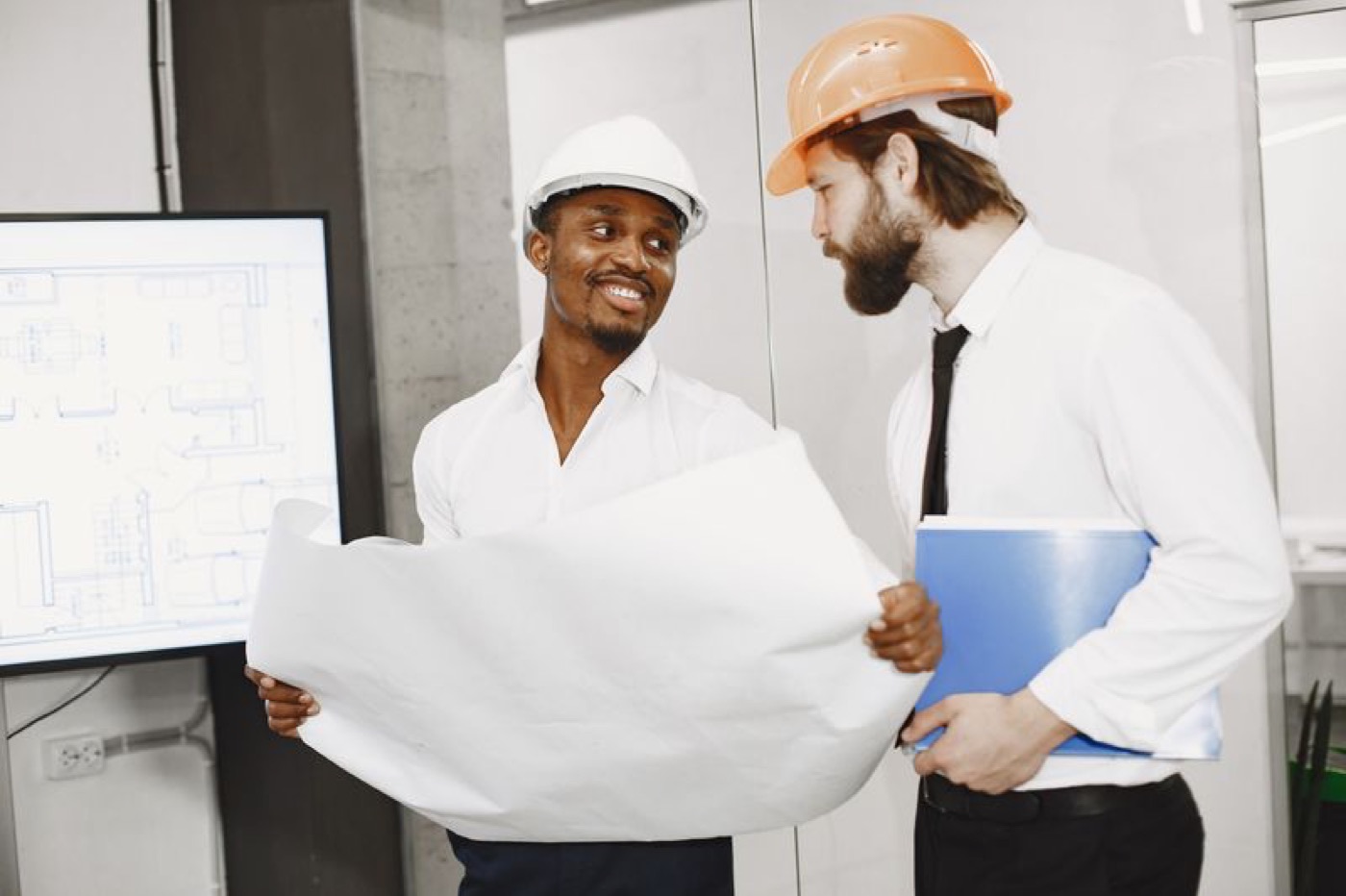 Two contractors in hard hats reviewing blueprints on site — illustrative stock photo