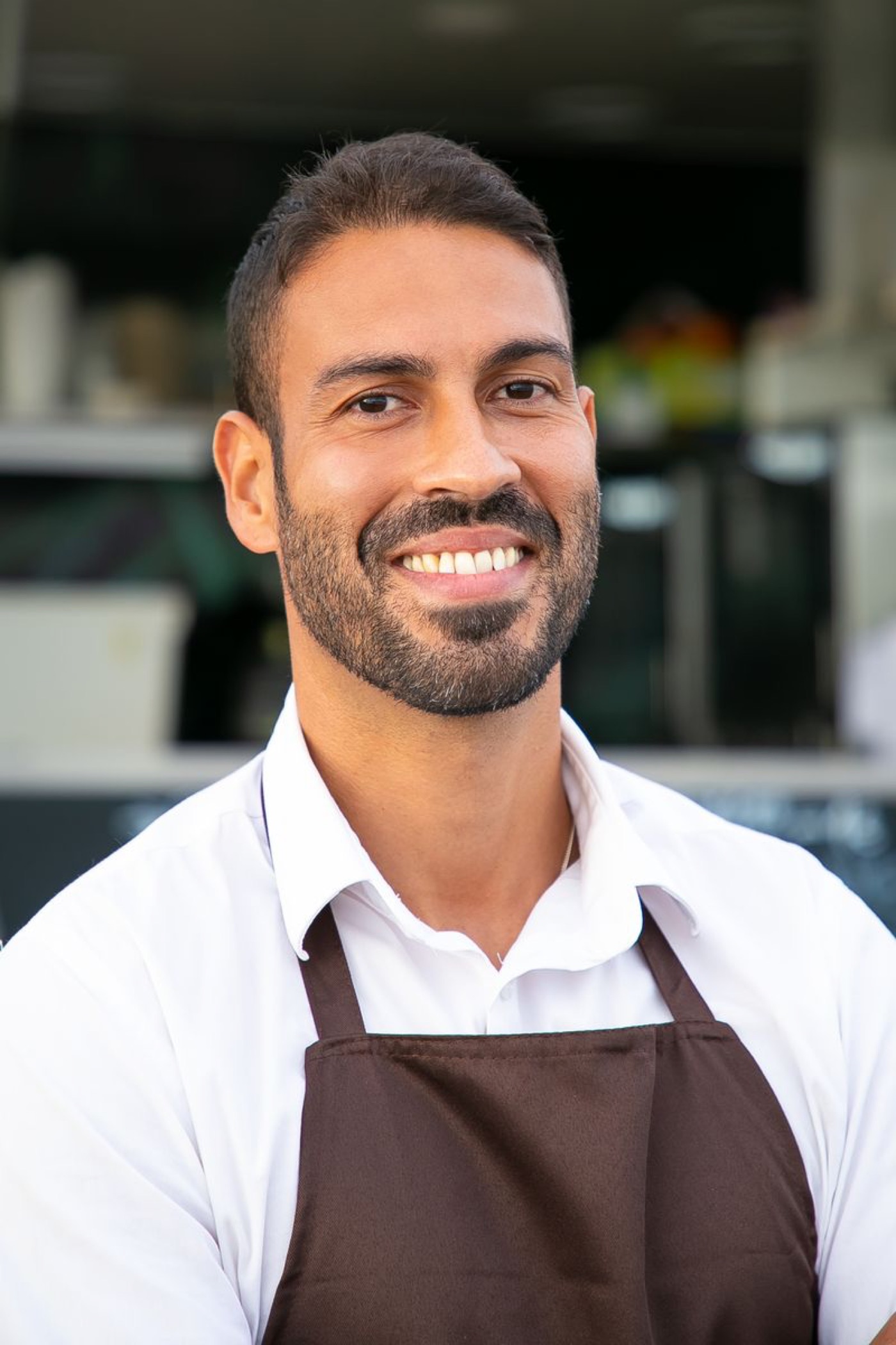 A smiling café owner in an apron — illustrative stock photo