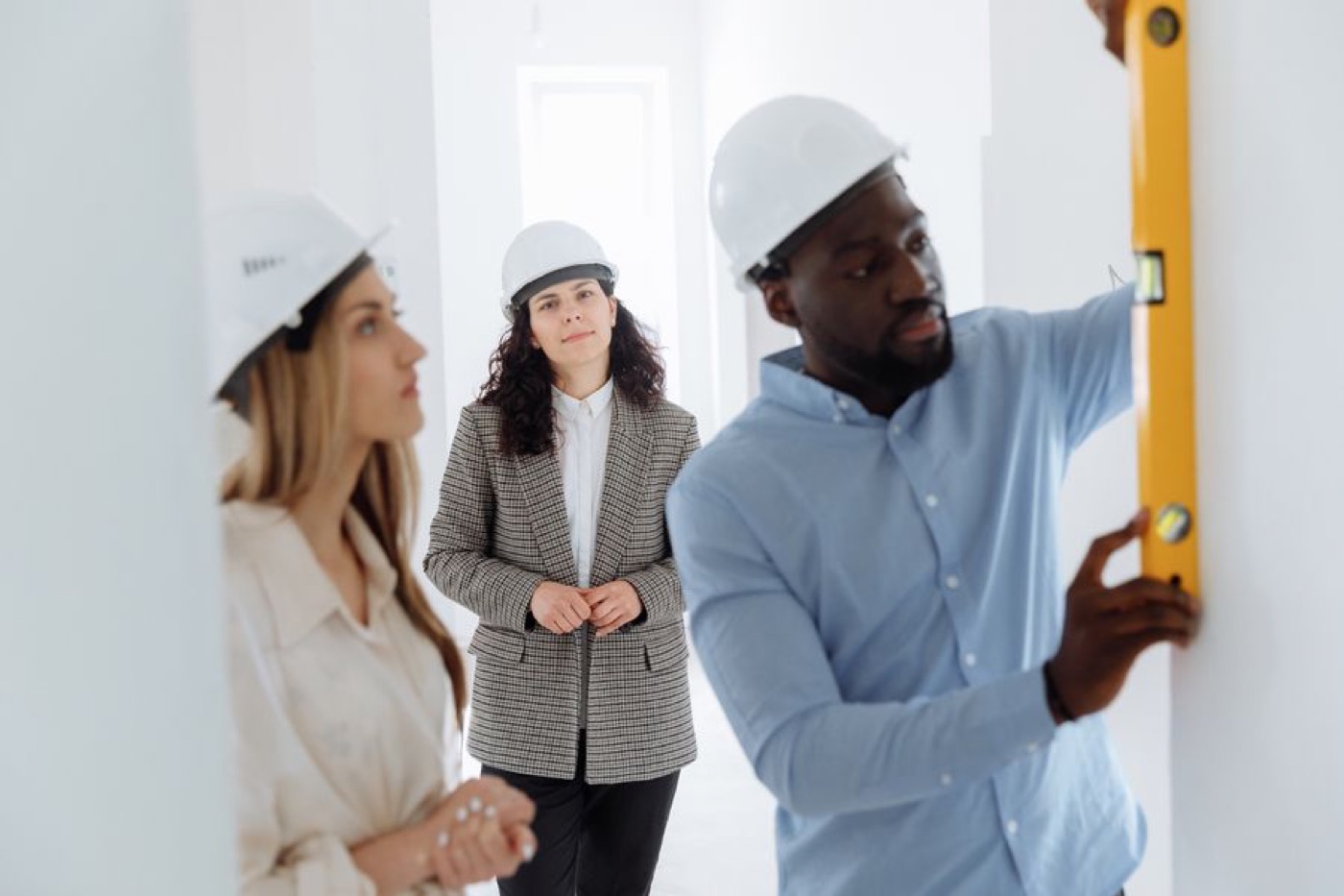 A contractor with a level walking clients through a renovation — illustrative stock photo