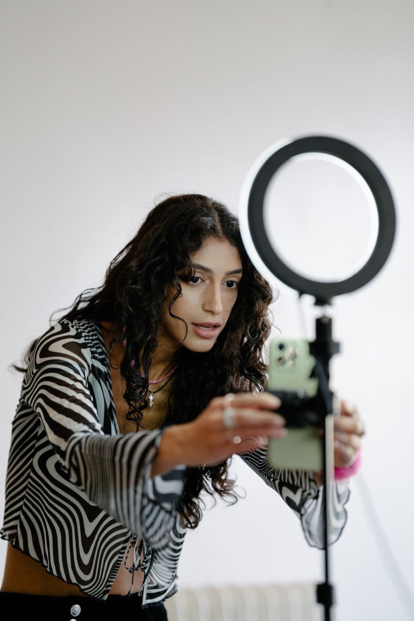 A creator setting up a smartphone on a ring-light tripod — illustrative stock photo